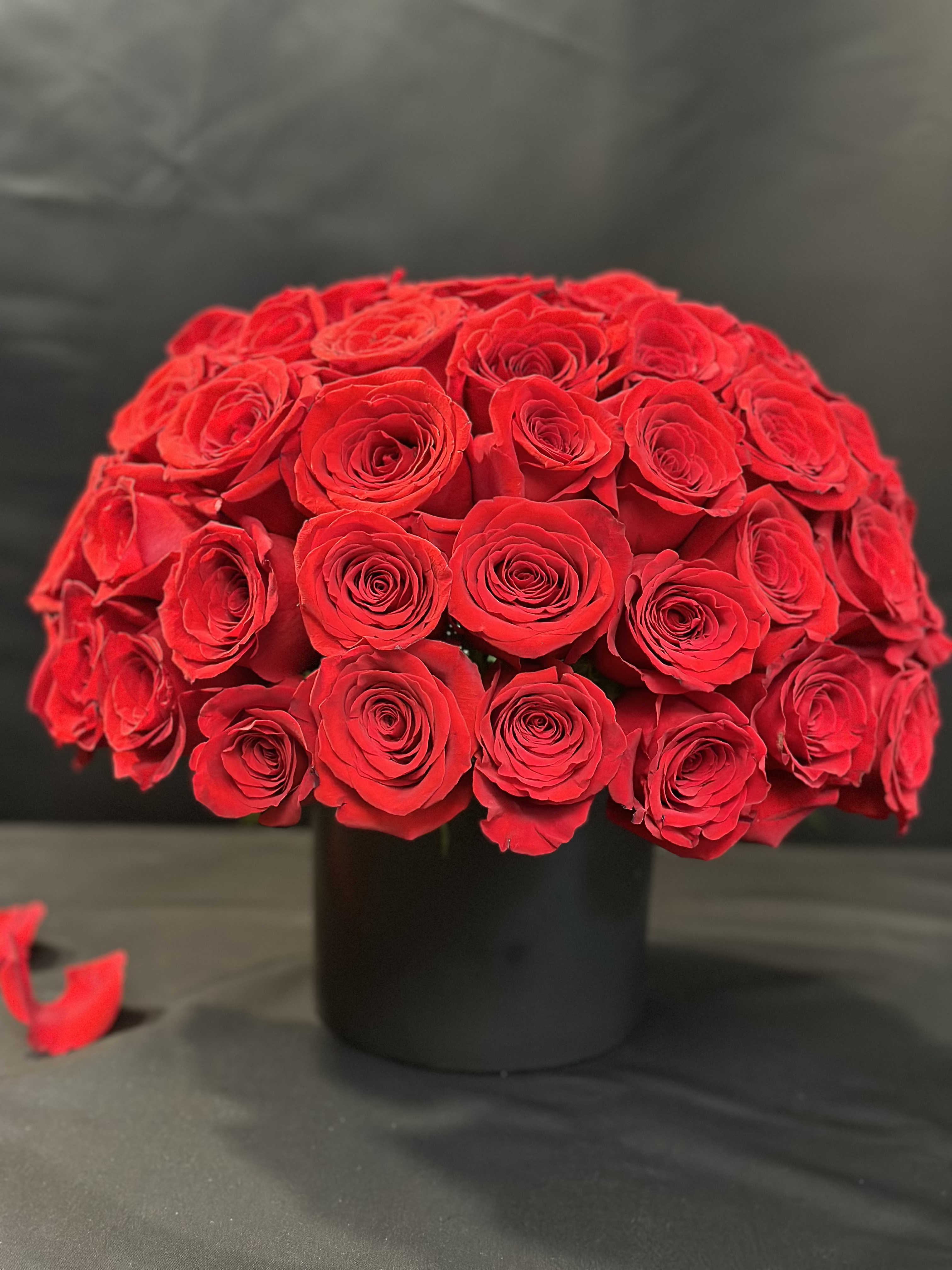 Round bouquet of red roses in a black vase