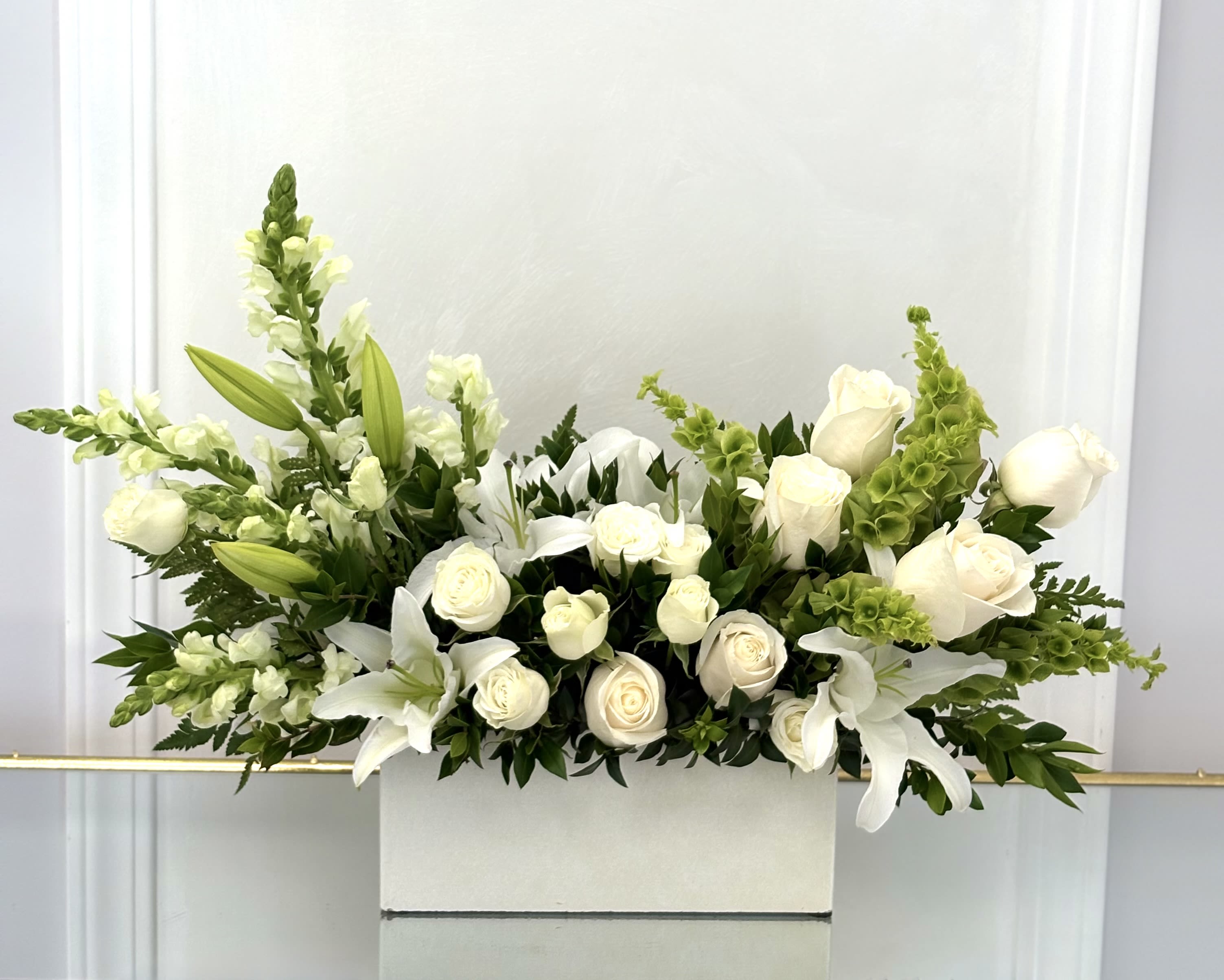 White roses and lilies arranged in a white rectangular box
