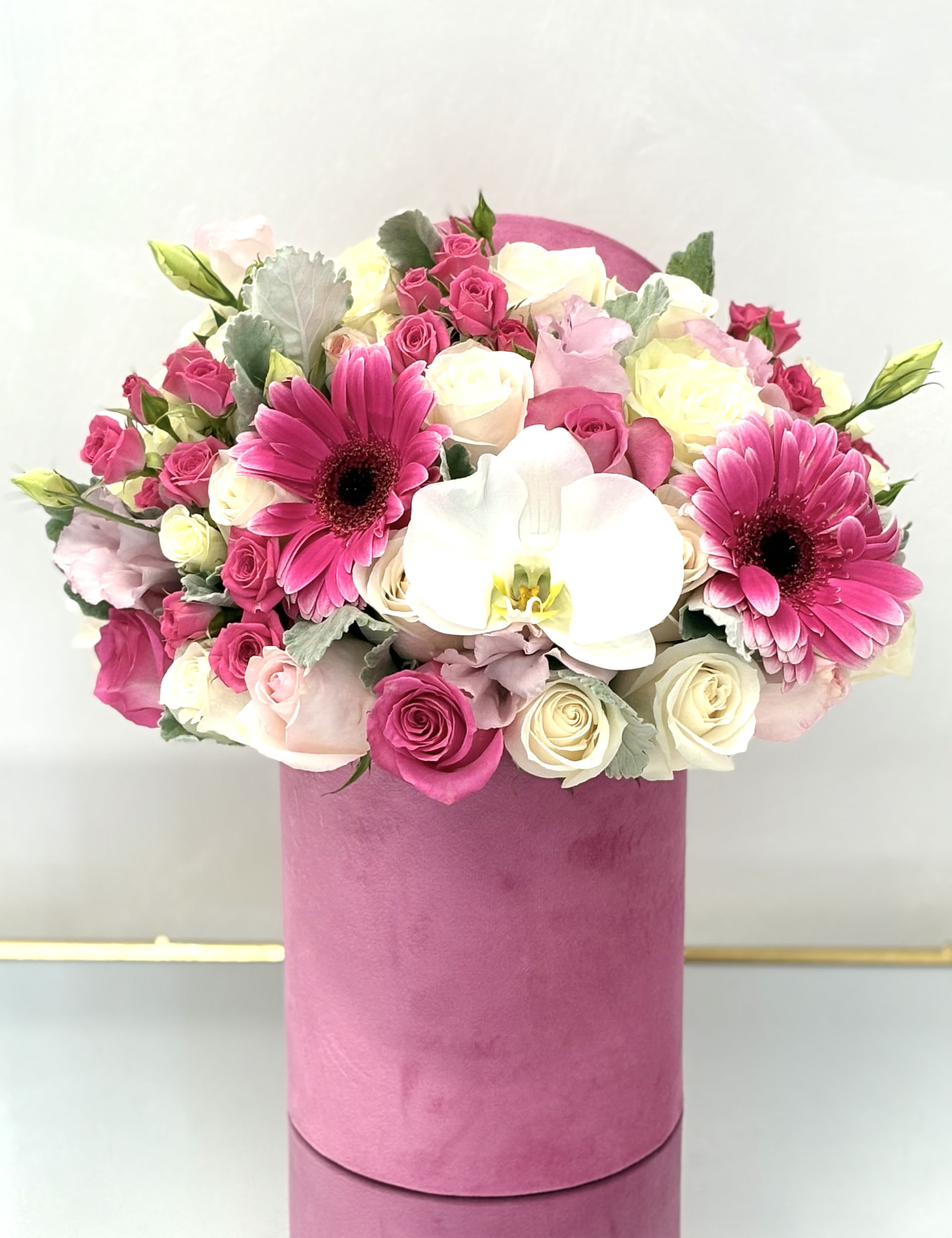 Pink and white bouquet with roses, gerbera daisies, and an orchid in a pink box