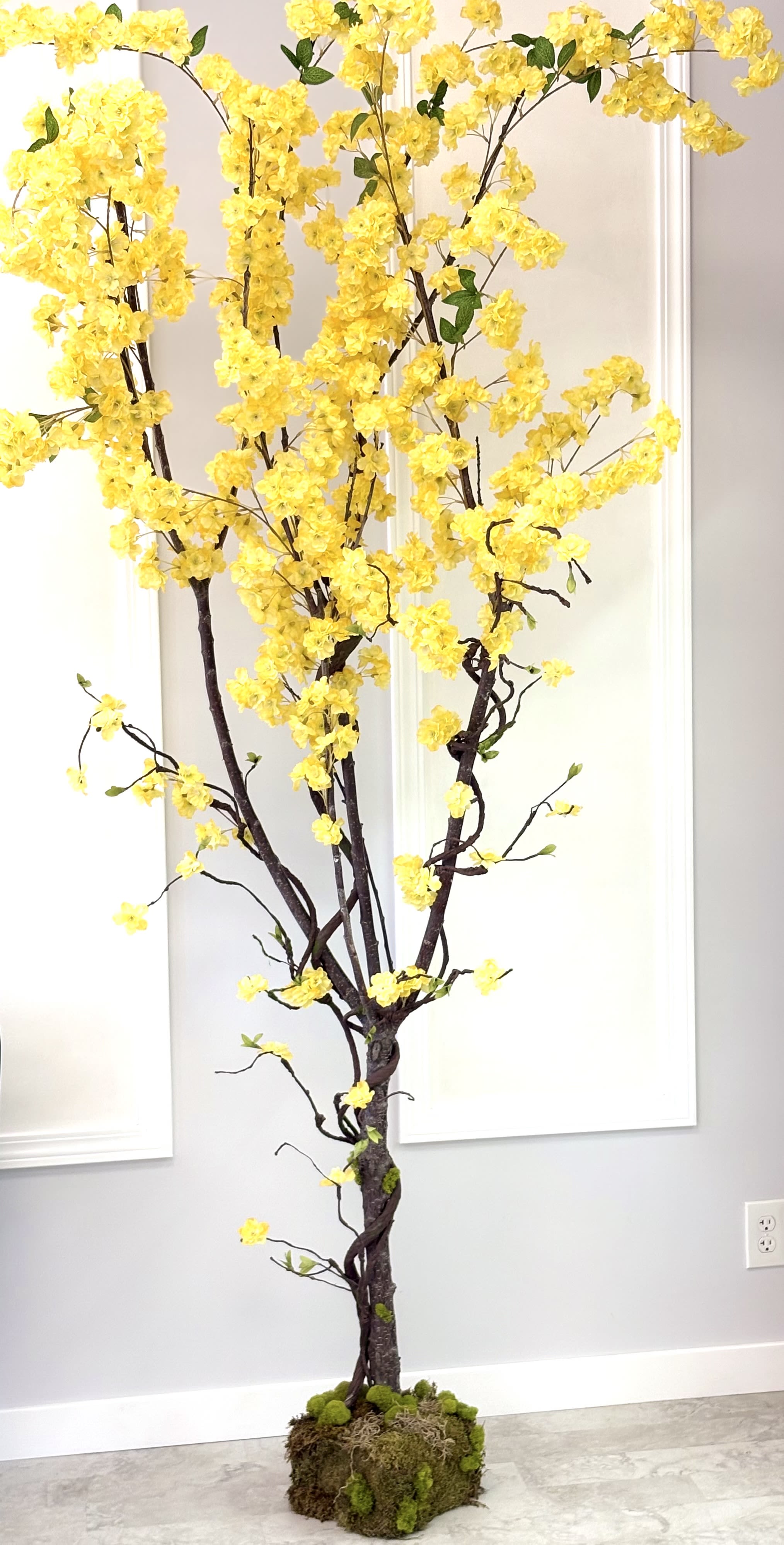 Tall yellow flowering tree arrangement in a moss-covered base