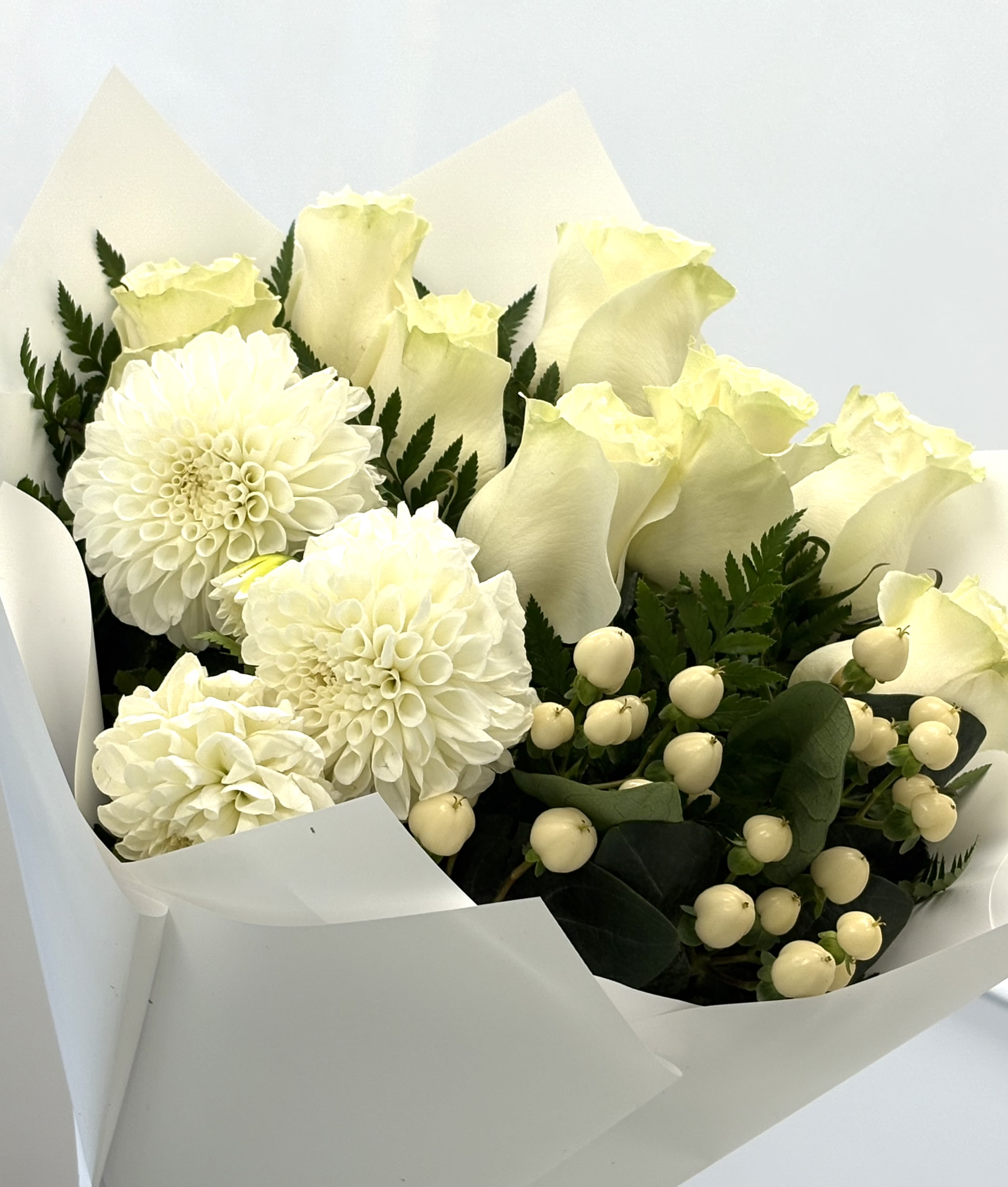 Pure Grace By VLM Flowers - A timeless expression of purity and elegance, Pure Grace features creamy white roses, delicate dahlias, and seasonal accents wrapped in crisp white paper. This bouquet is perfect for weddings, sympathy, or simply saying “thinking of you” with quiet beauty.