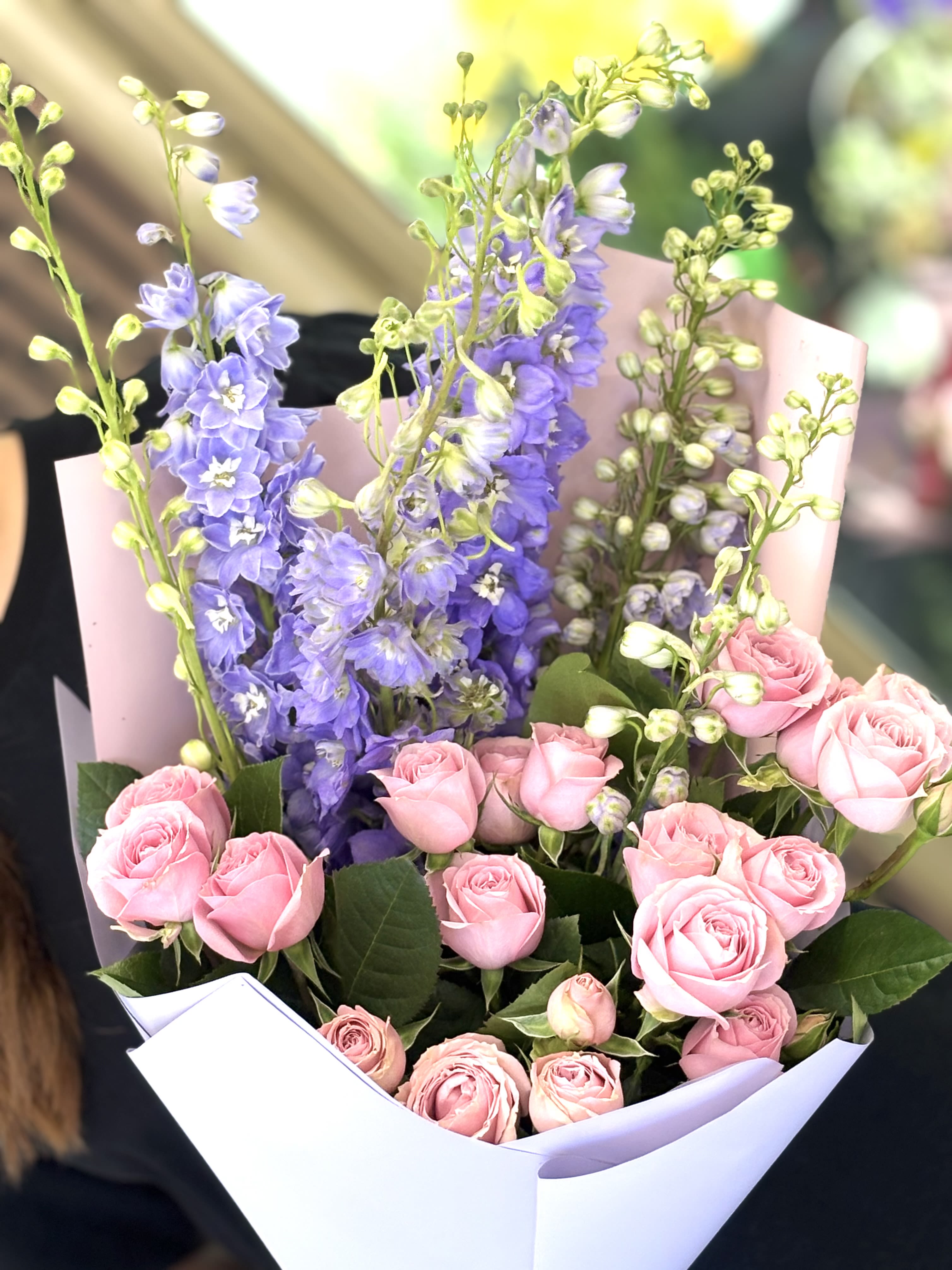 Bouquet of pink roses and purple delphinium in white wrap