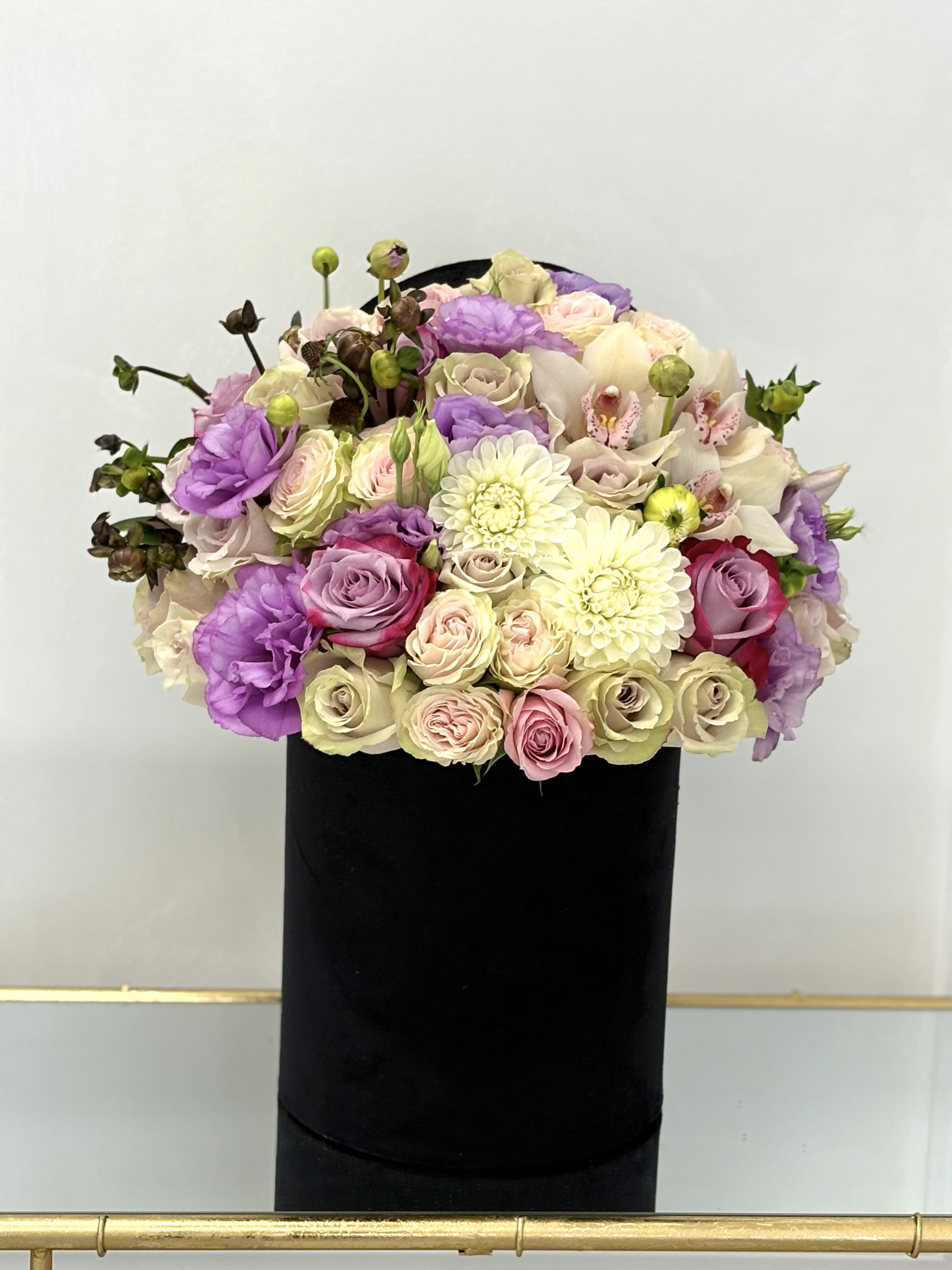Bouquet of pastel roses, orchids, and white dahlias in a black box