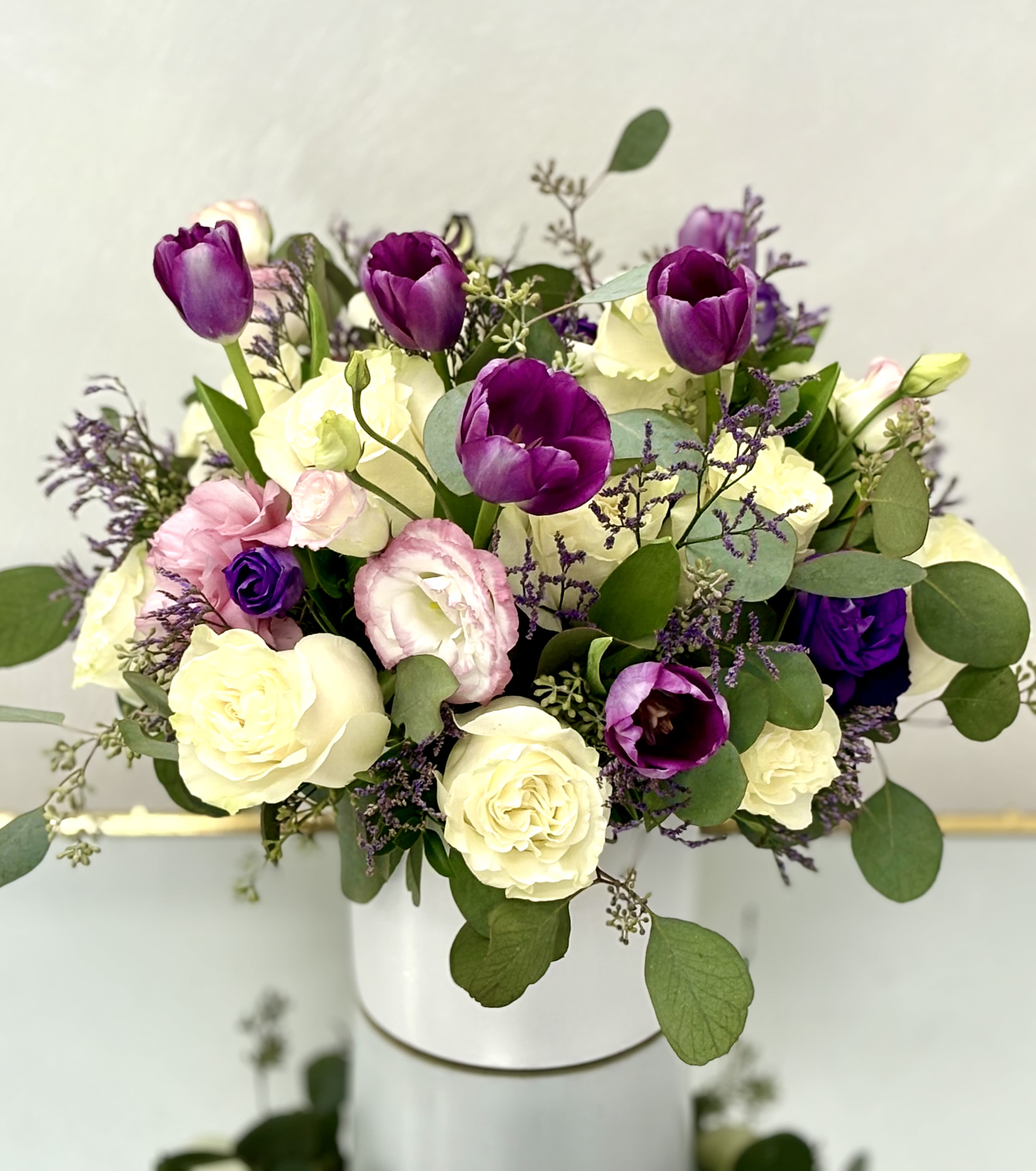 Purple Serenade By VLM Flowers - A graceful mix of violet tulips, lisianthus, and ivory roses accented with soft greenery. Elegant and romantic, this arrangement is perfect for celebrating love, admiration, or any special moment.