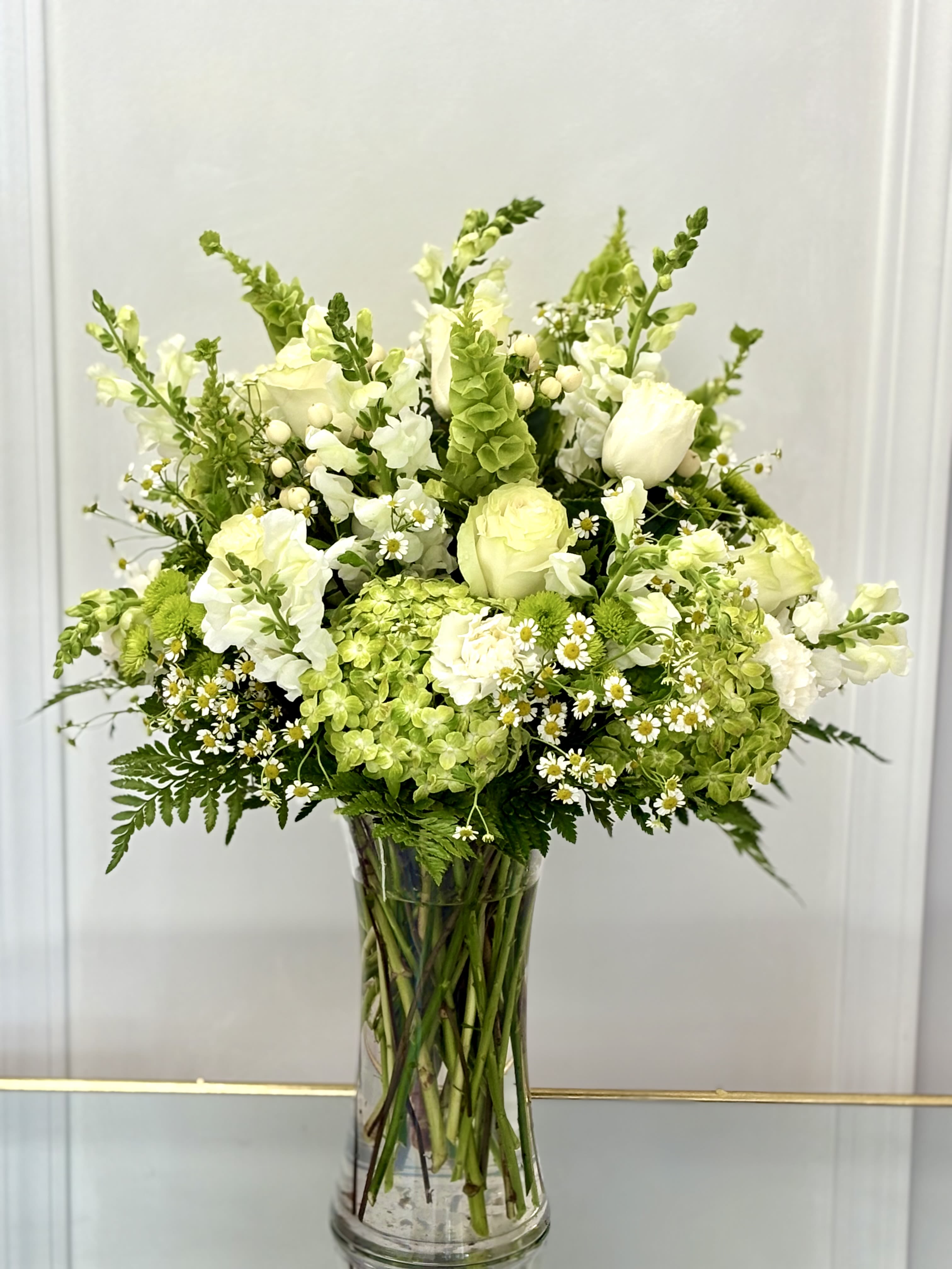 White and green bouquet in a clear glass vase