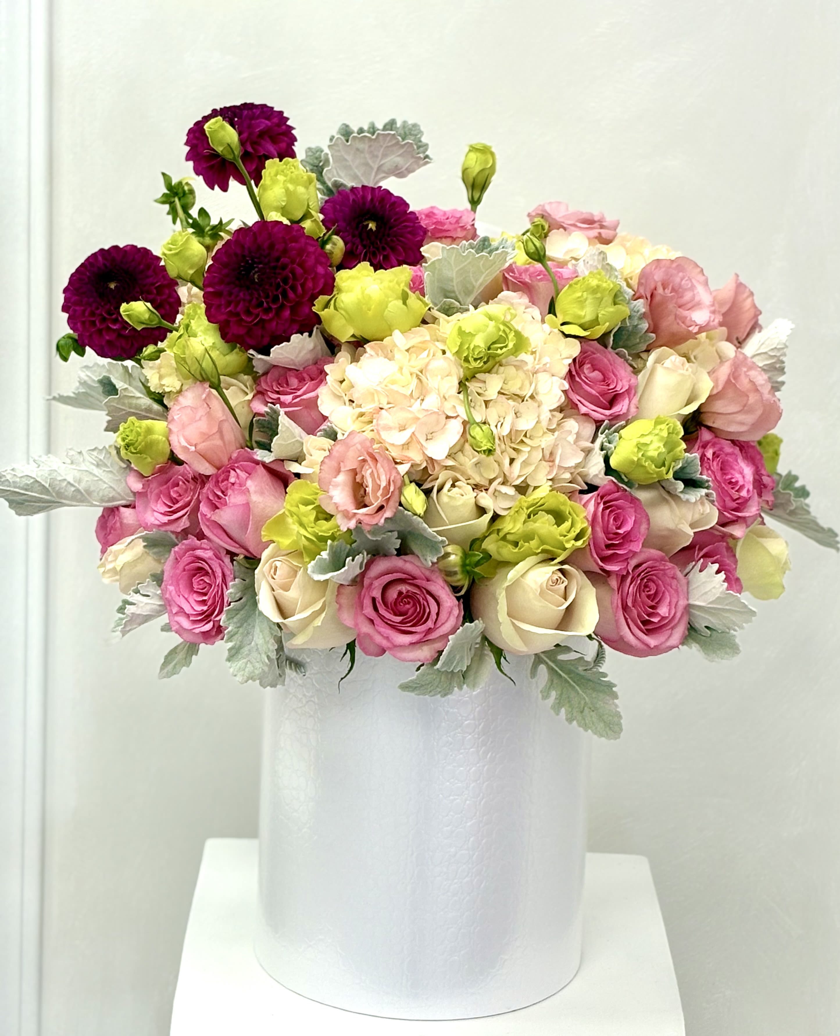 Pink and cream bouquet with lime accents in a white vase