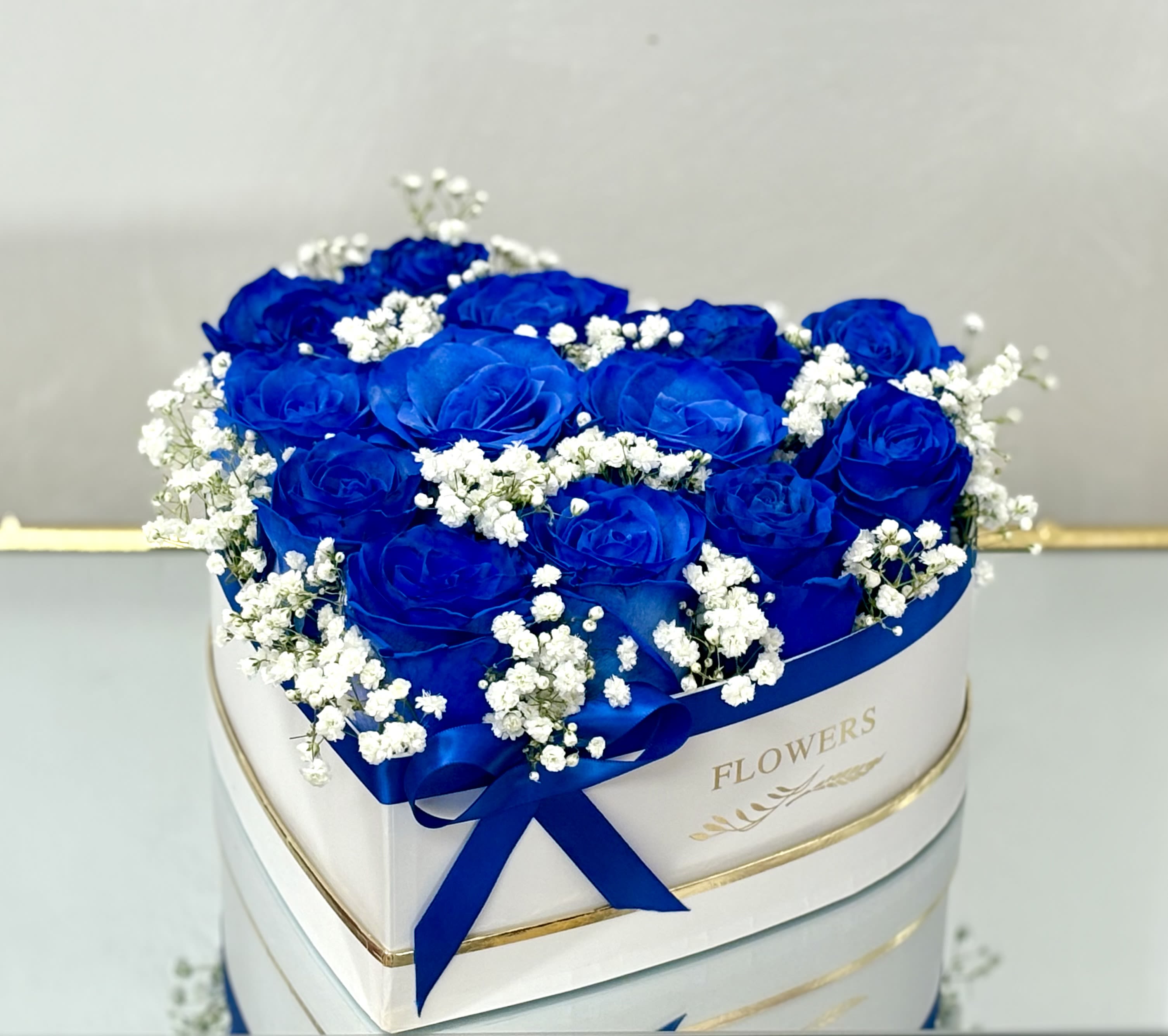 Blue roses with white baby's breath in a round white box