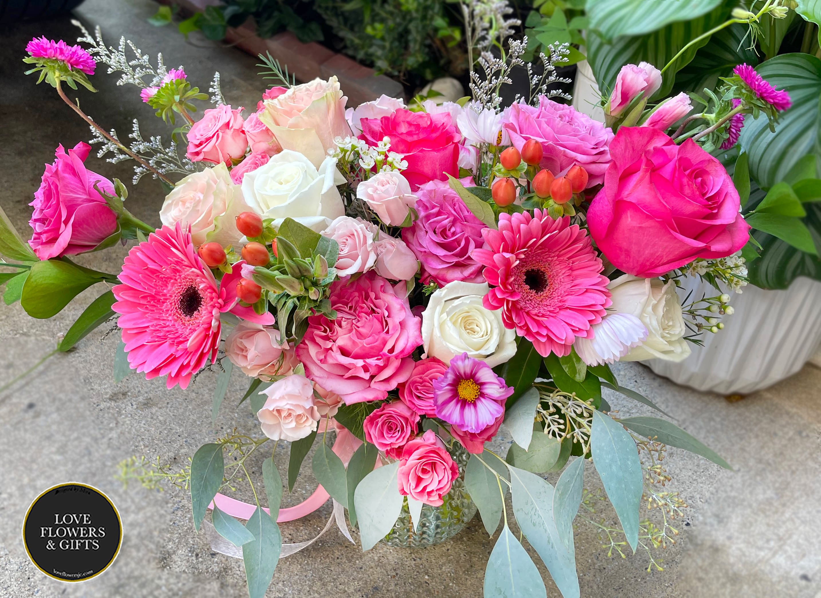 Vase arrangement of hot pink and white roses with pink gerbera daisies and mixed blooms.