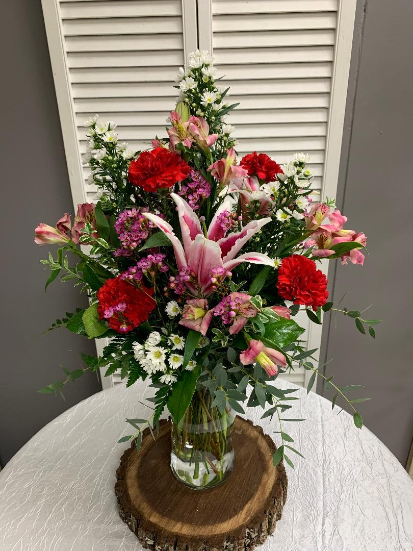 Date in the Garden Arrangement - This arrangement includes Pink Alstromerias, Red Carnations, Stargazer Lily, Monte Casino and Wax Flower. Lily color may vary from photo
