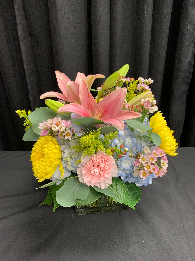 Pink lilies and mixed blooms in a glass vase