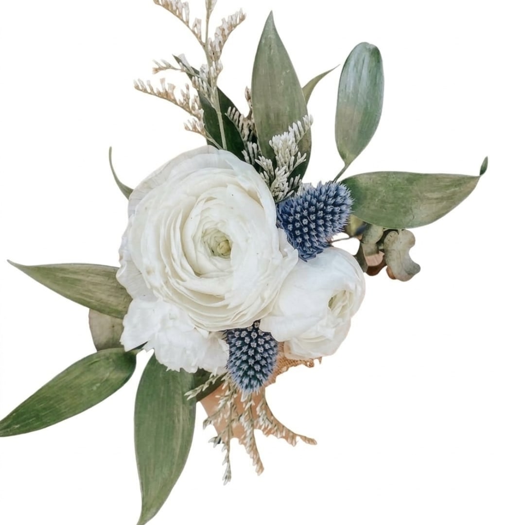 White ranunculus boutonniere with blue thistle and green leaves
