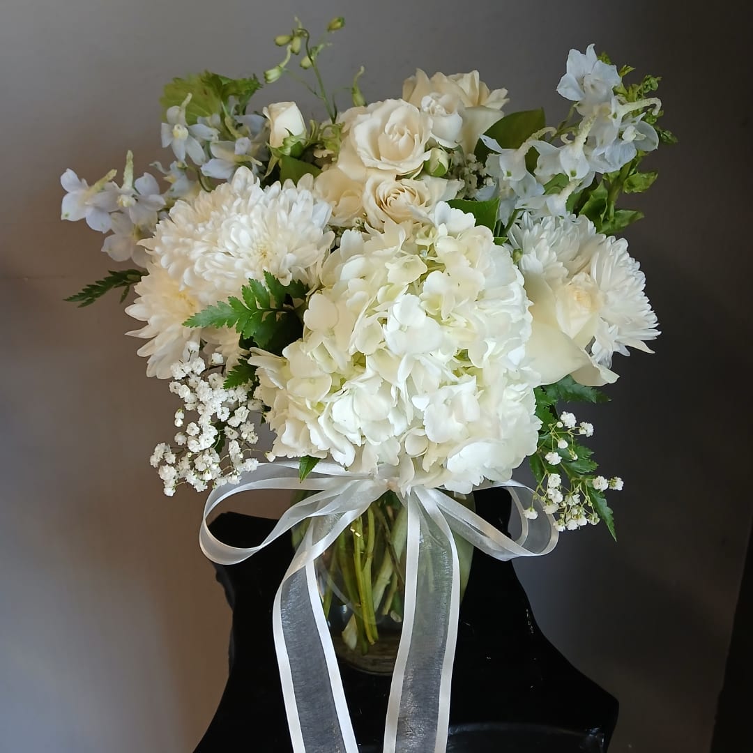 White floral bouquet in a glass vase with a white ribbon