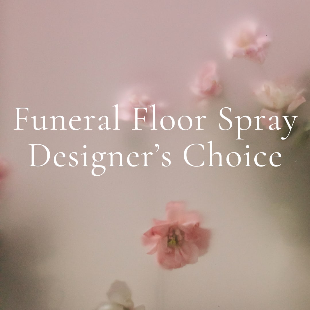 Pink floral funeral floor spray with soft blossoms on a pale background