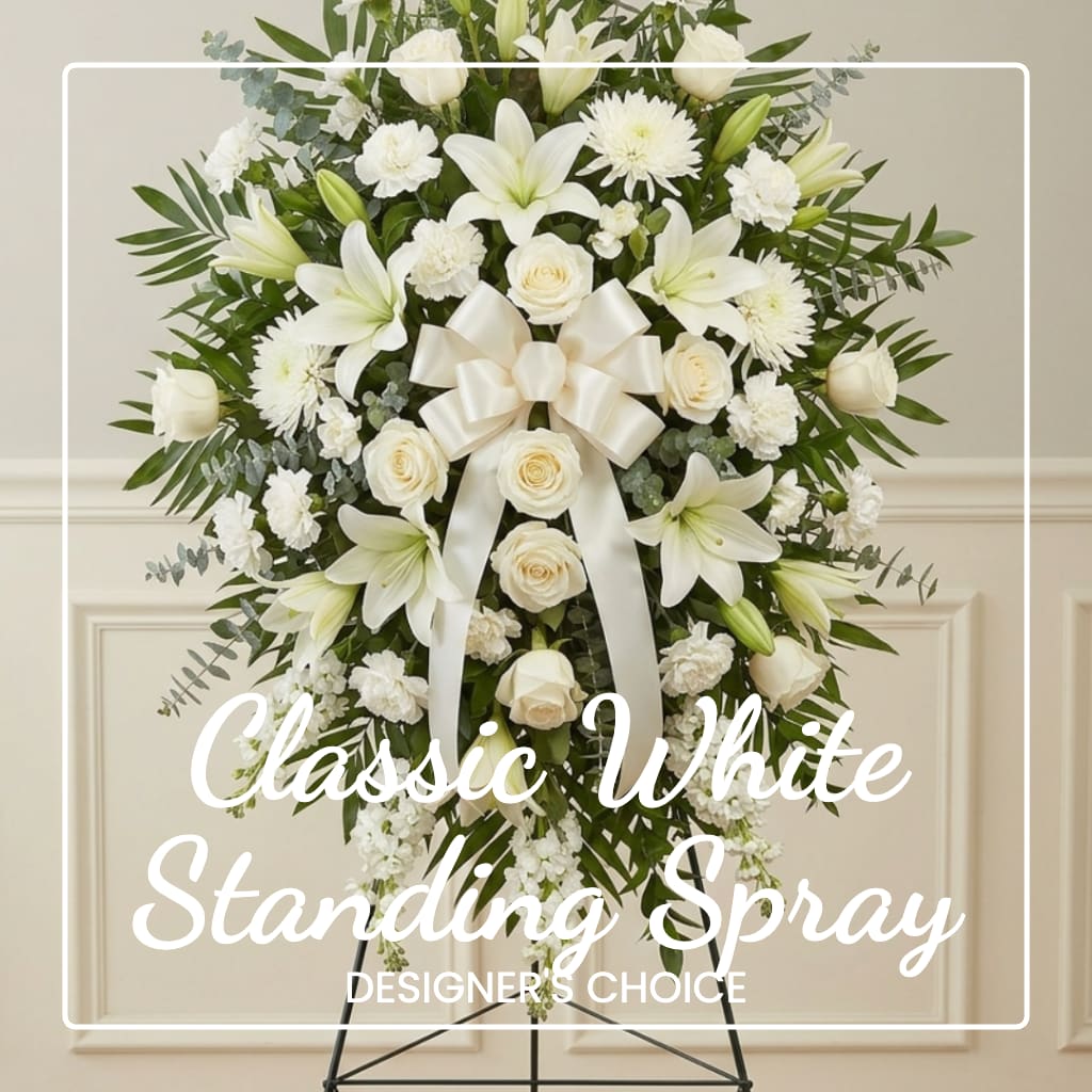 White standing spray with lilies, roses, and a ribbon on an easel