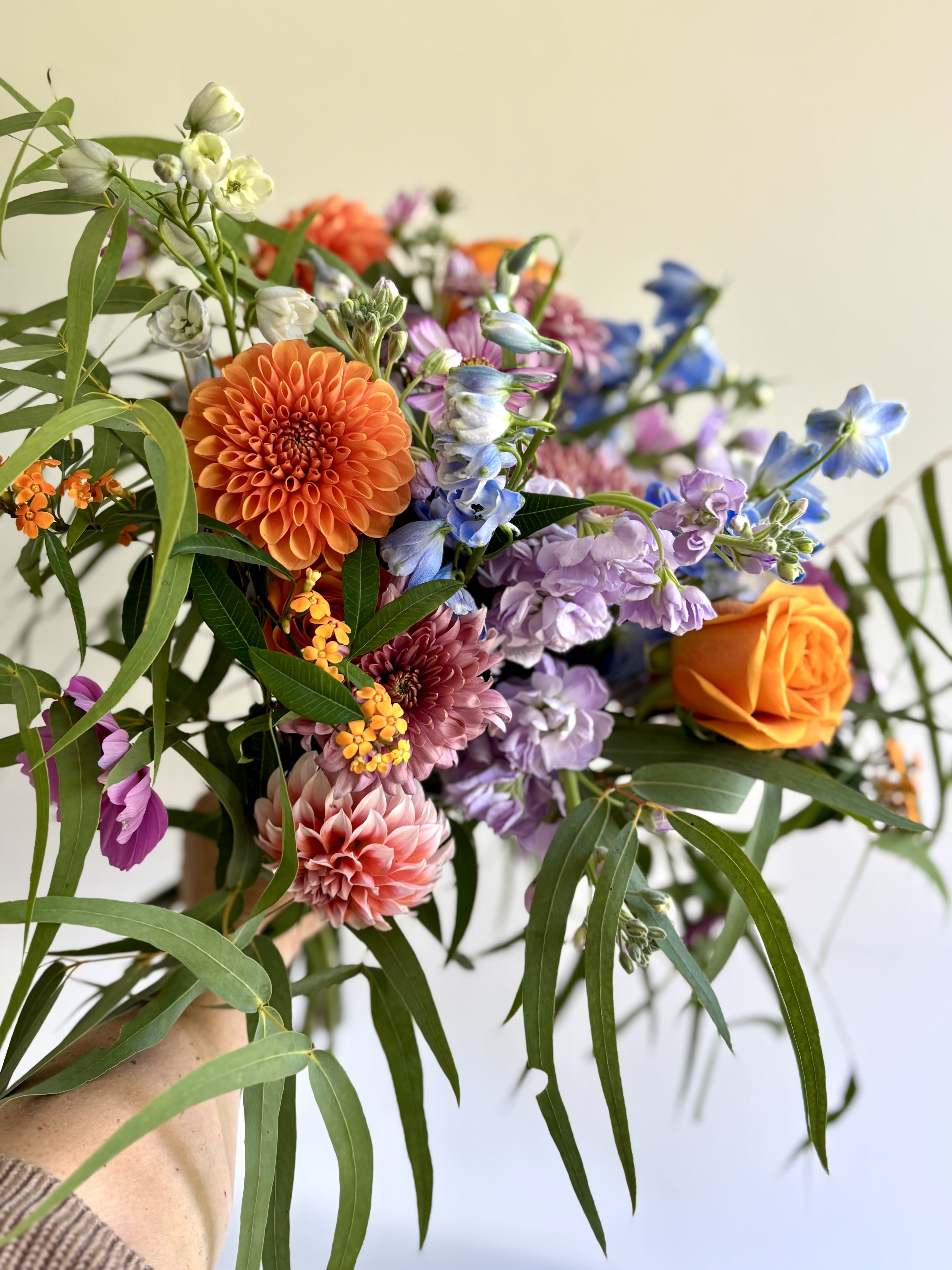 Handheld bouquet with orange, purple, pink, and blue flowers