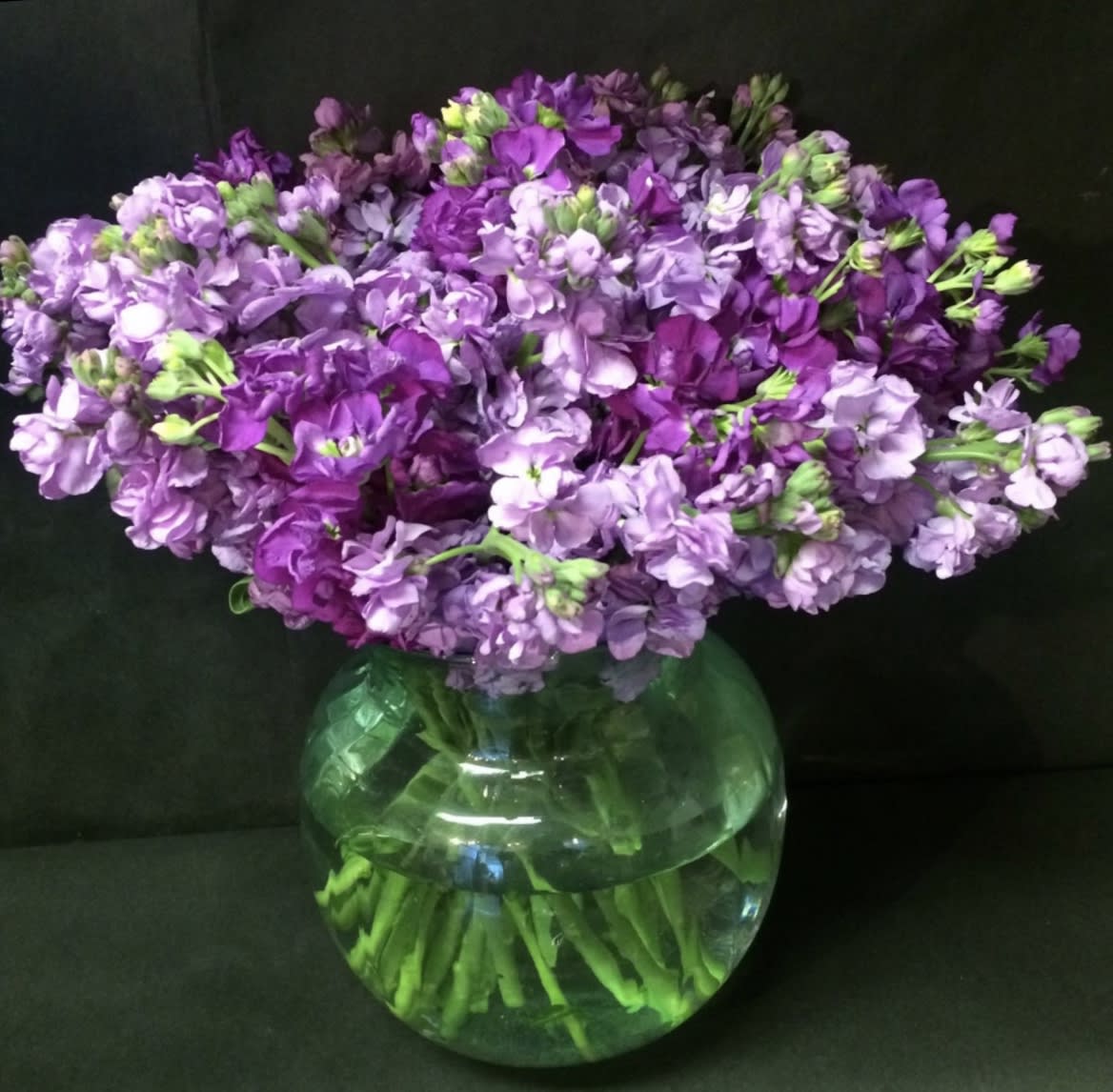 Purple flowers arranged in a round glass vase