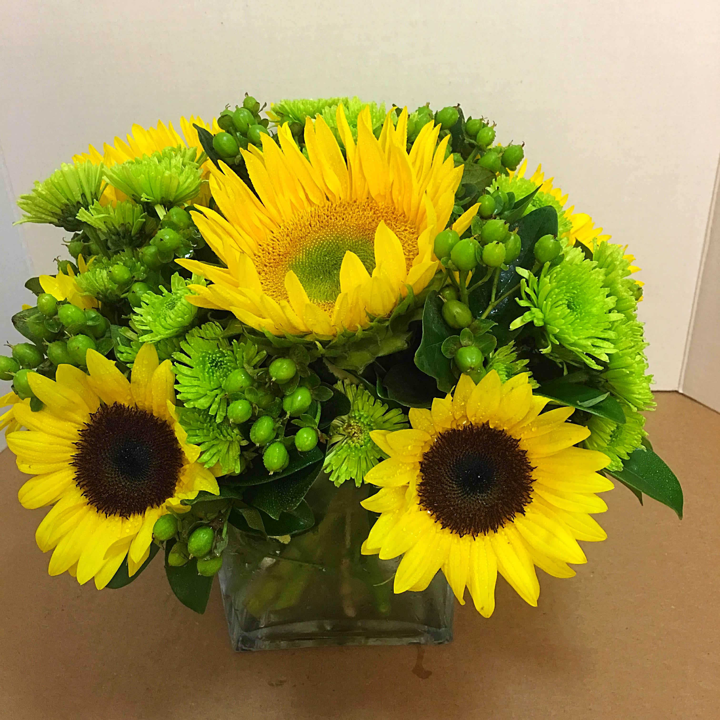 Florida Sunshine - Send this Florida Sunshine to someone special and it is sure to brighten their day.  This clear cube packed with medium and large sunflowers, engulfed by green hypericum makes a one of a kind gift. 