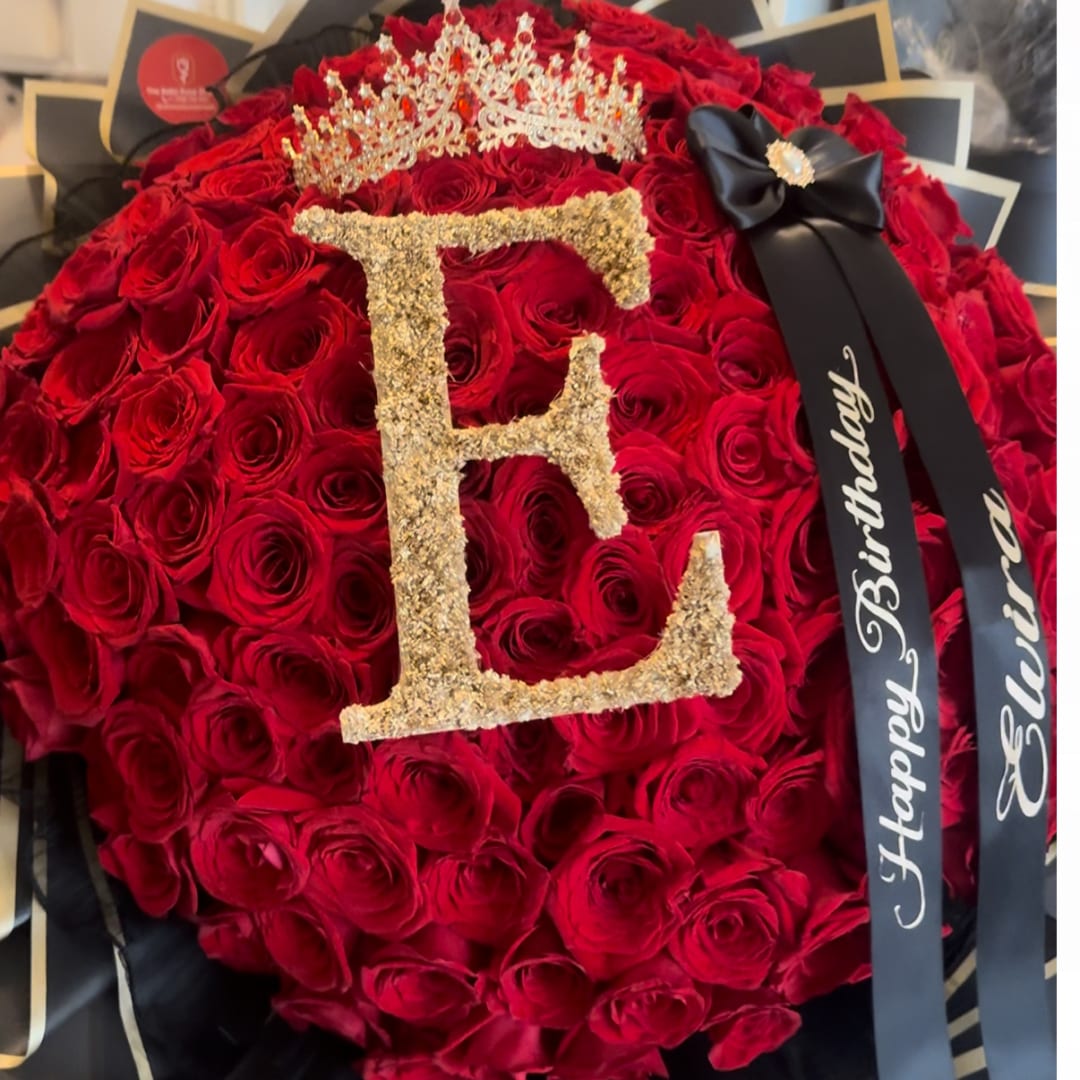 Heart-shaped bouquet of red roses with a gold letter E and birthday ribbon