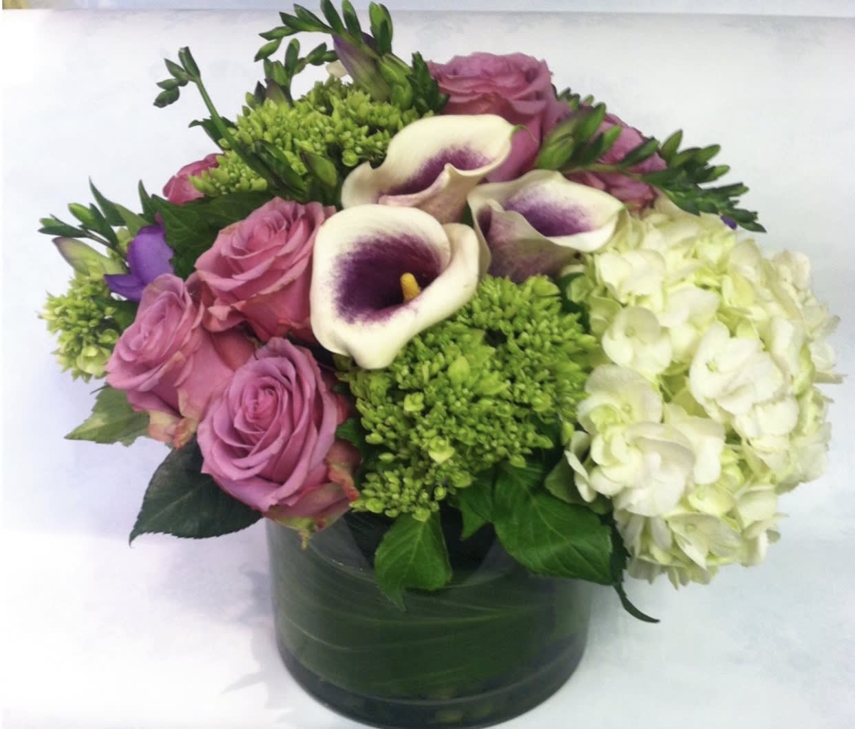 Pink roses and white calla lilies in a green vase