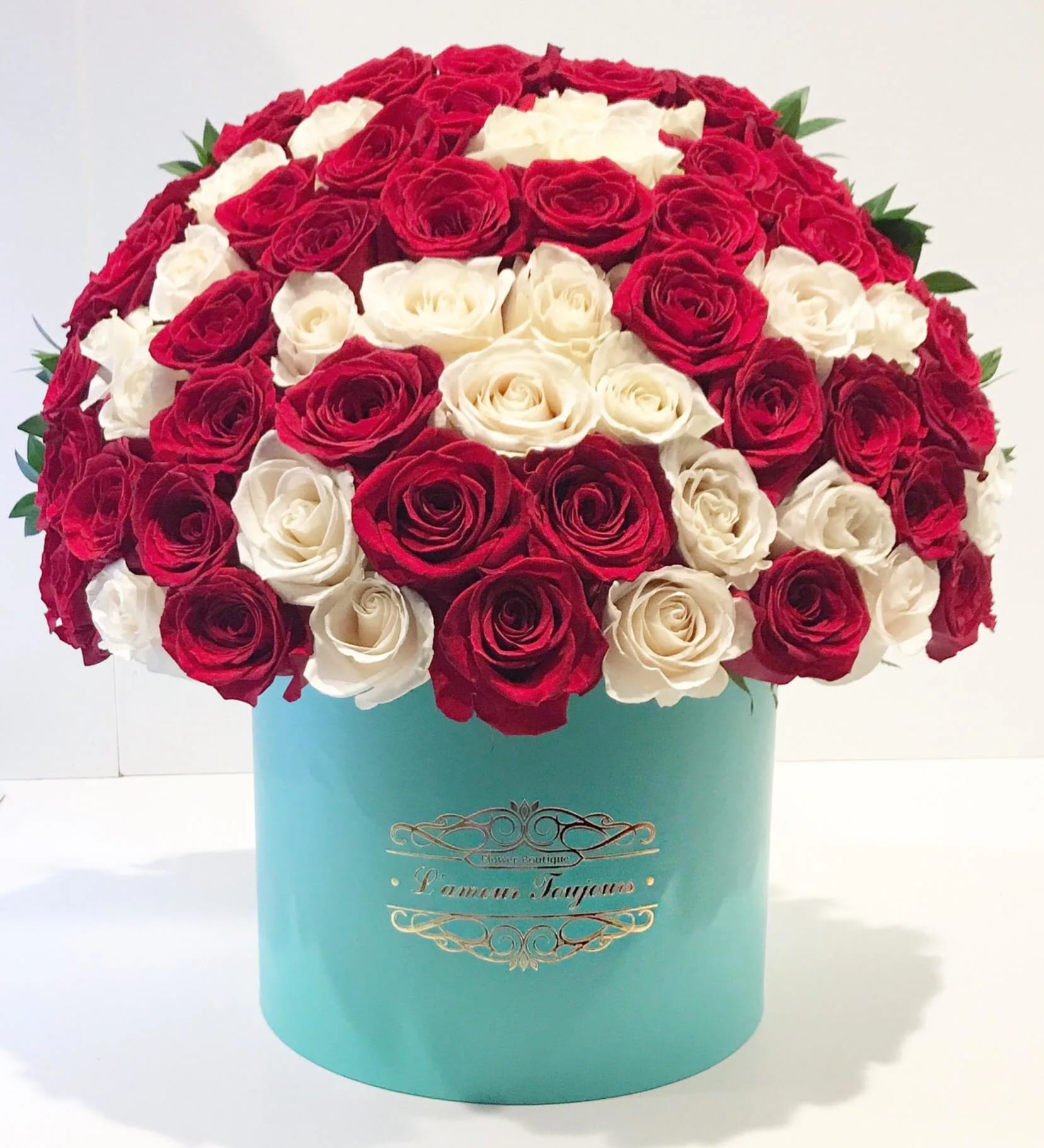 Red and white roses arranged in a turquoise hat box