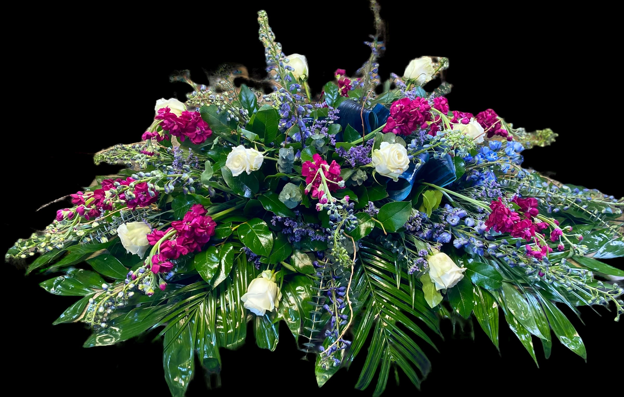 Eternal Glory  - A timeless expression of peace and purity, the Eternal Glory casket spray features a lush collection of blooms. Designed to span the full length of the casket, this arrangement is filled with roses, carnations, snapdragons, and seasonal white florals, accented with soft greenery for a serene and comforting tribute.