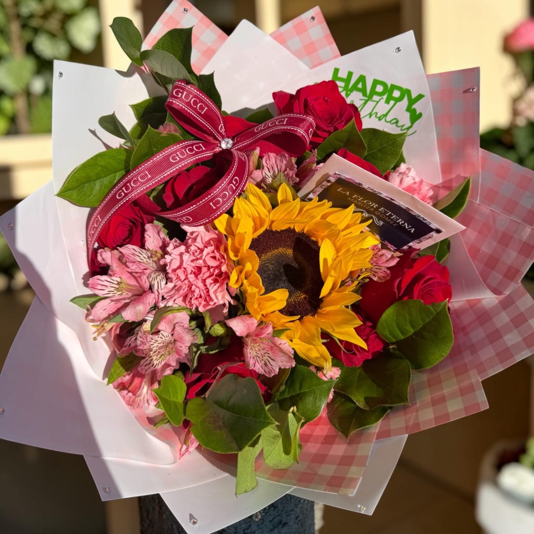 Bouquet of red roses, pink flowers, and a sunflower with a ribbon