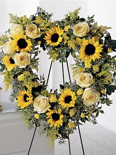 Heart-shaped floral wreath with sunflowers and cream roses on a stand