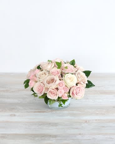 Low bouquet of pale pink and white roses in a clear glass bowl