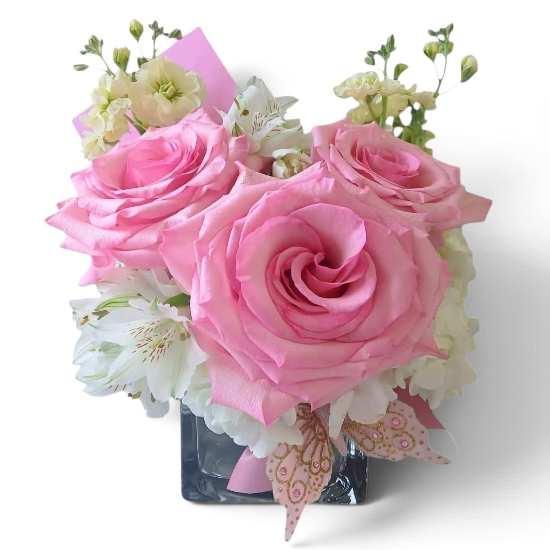 Pink roses and white flowers arranged in a square glass vase