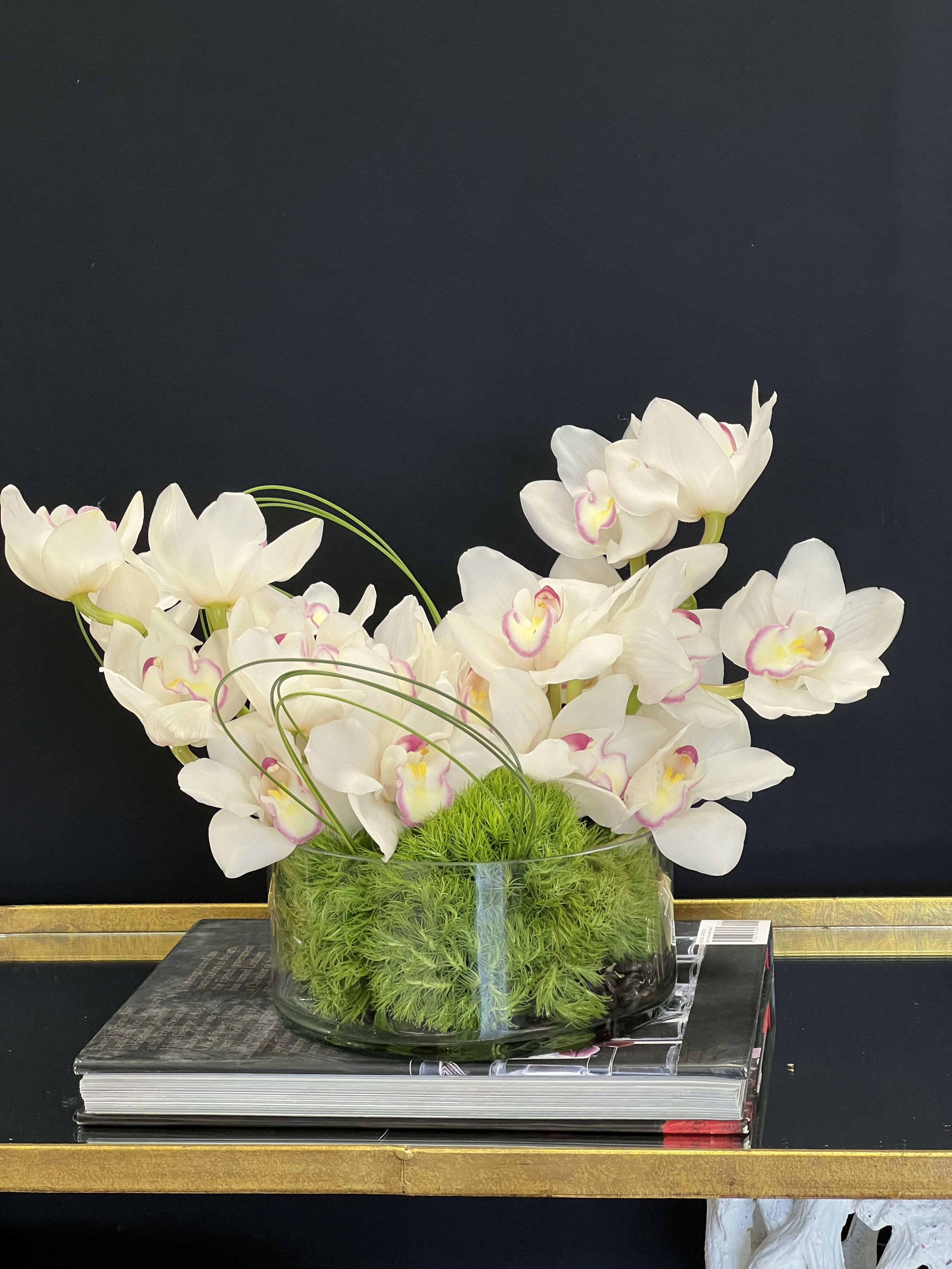 White orchids arranged in a glass bowl with green moss
