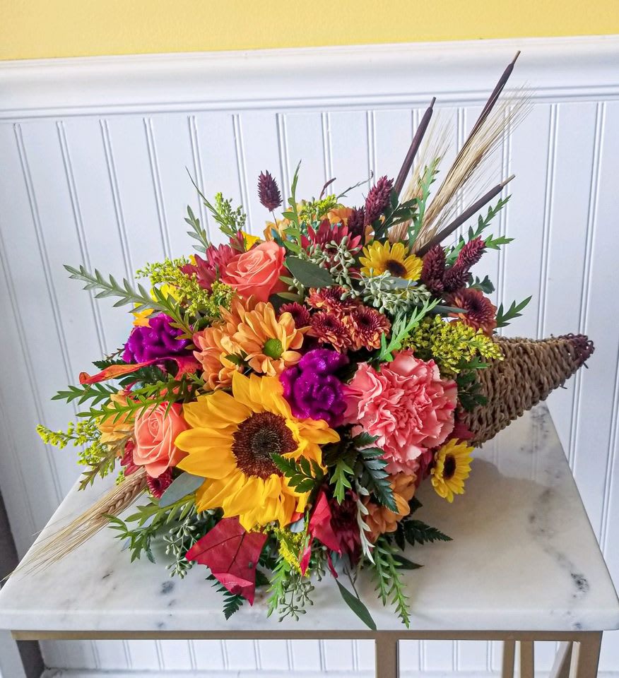 Colorful bouquet with sunflowers, roses, and carnations in a woven cone wrap