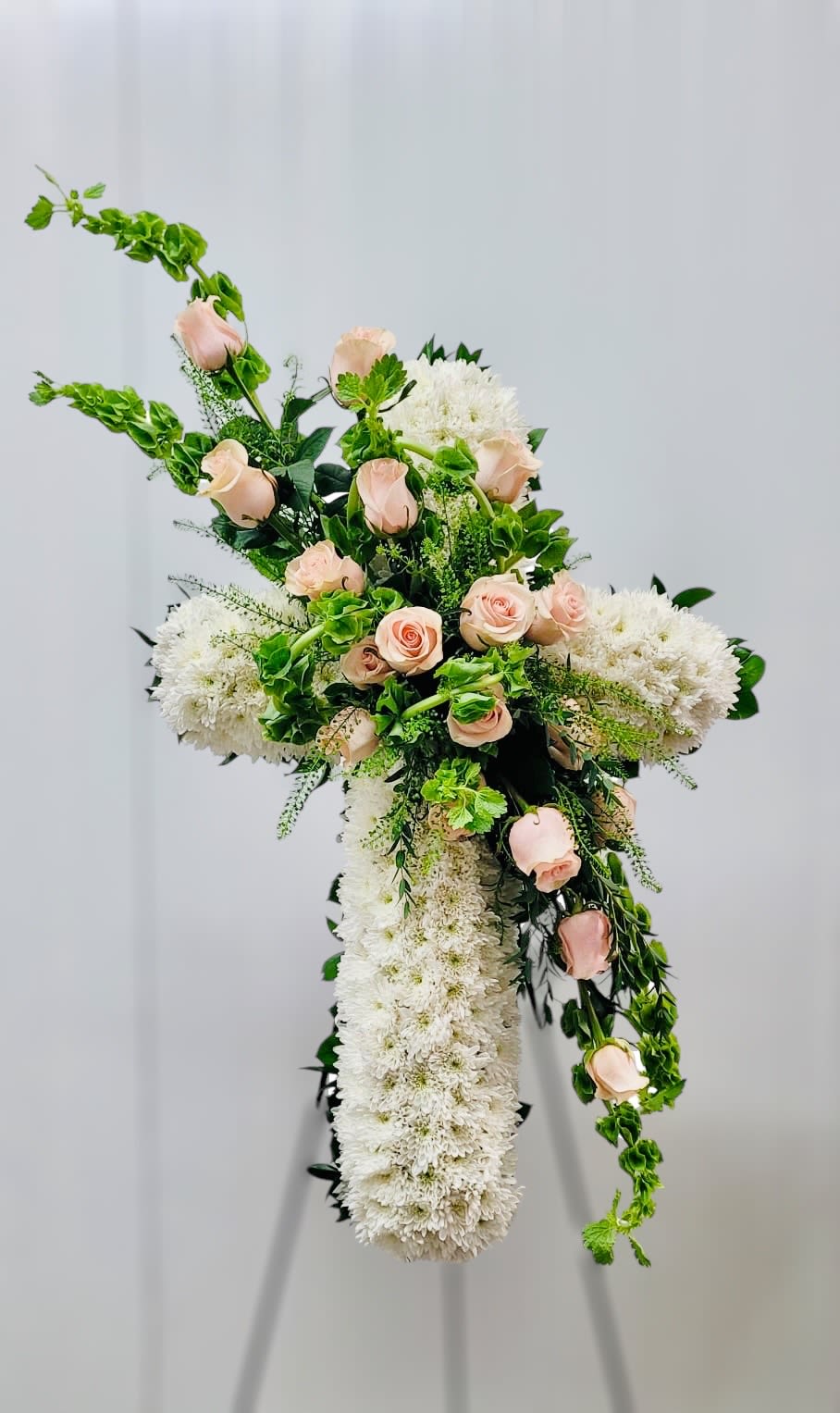 Cross-shaped floral arrangement with pale pink roses and white blooms