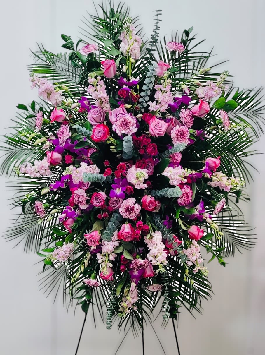 Large standing spray of pink and purple flowers with palm fronds