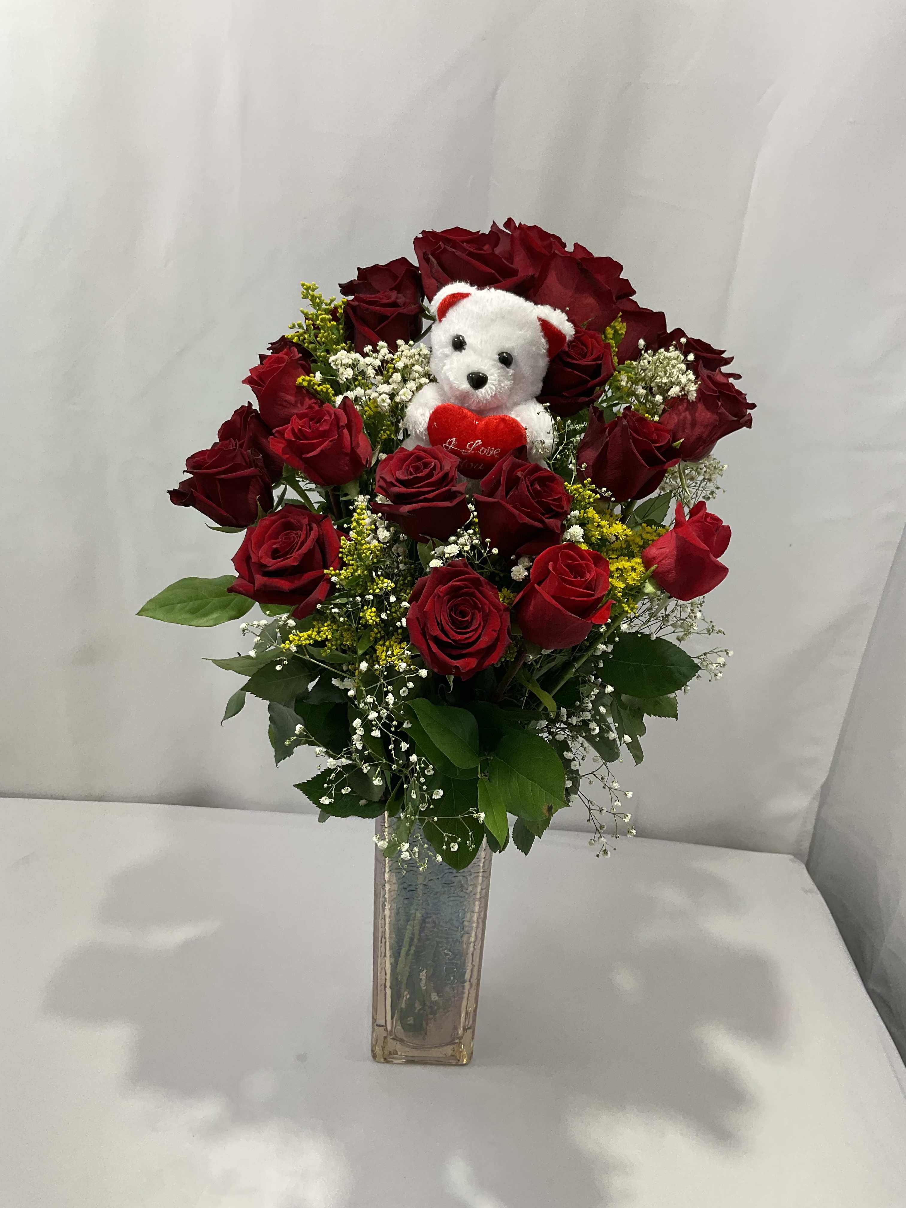 Red rose bouquet in a clear vase with a small teddy bear
