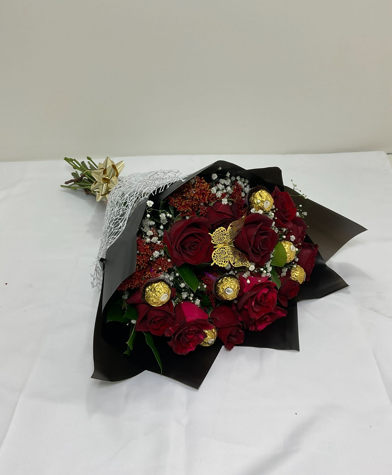 Bouquet of red roses with gold-wrapped chocolates in black paper