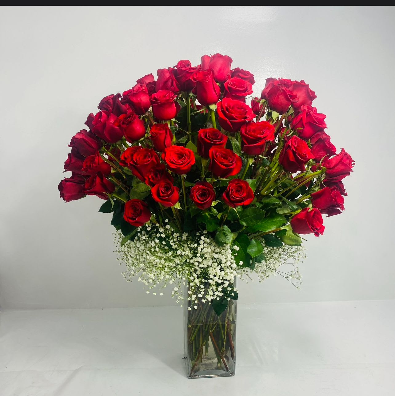 Bouquet of red roses in a clear glass vase with white baby's breath