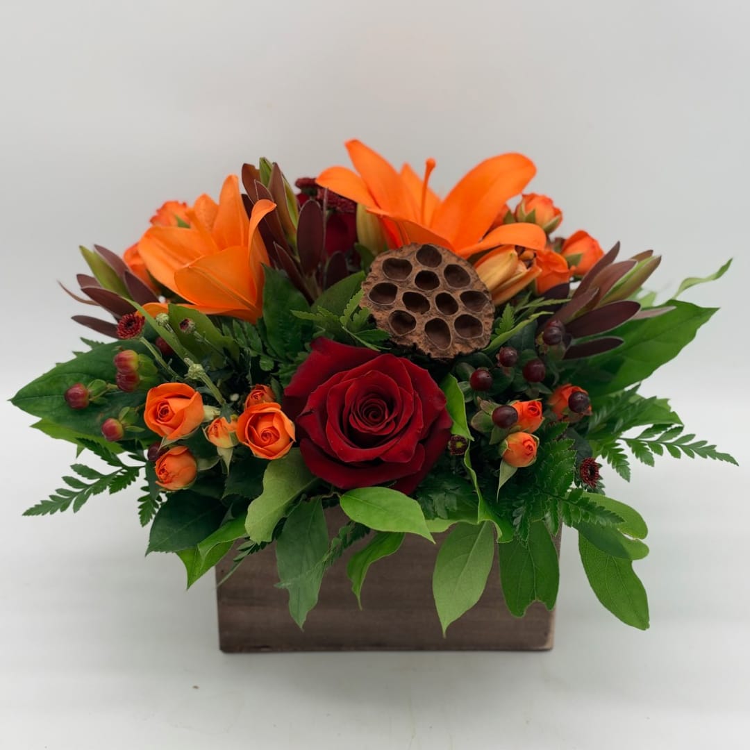 Orange lilies and red roses arranged in a wooden box