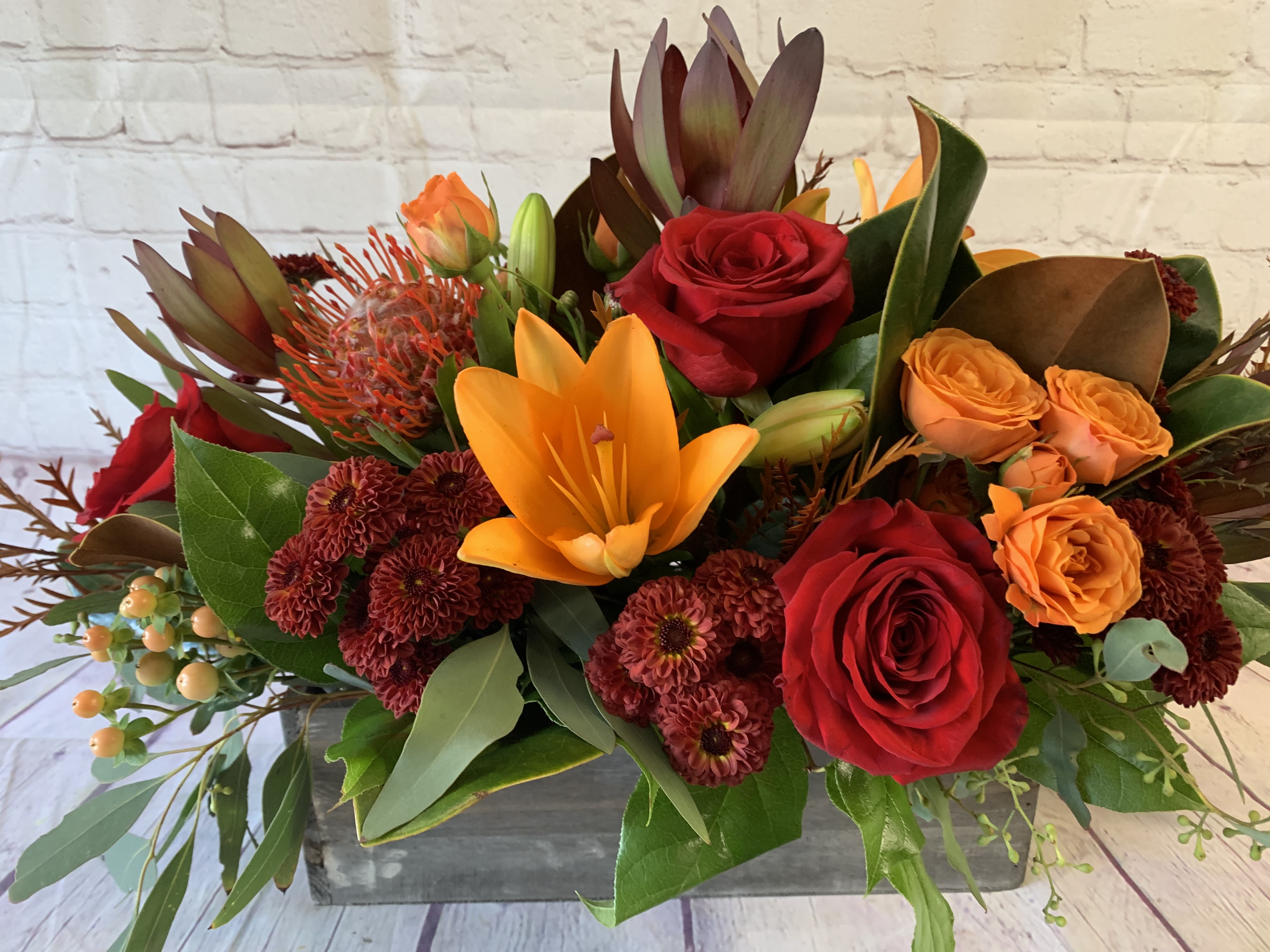 Mixed bouquet with red and orange roses, lilies, and dark mums