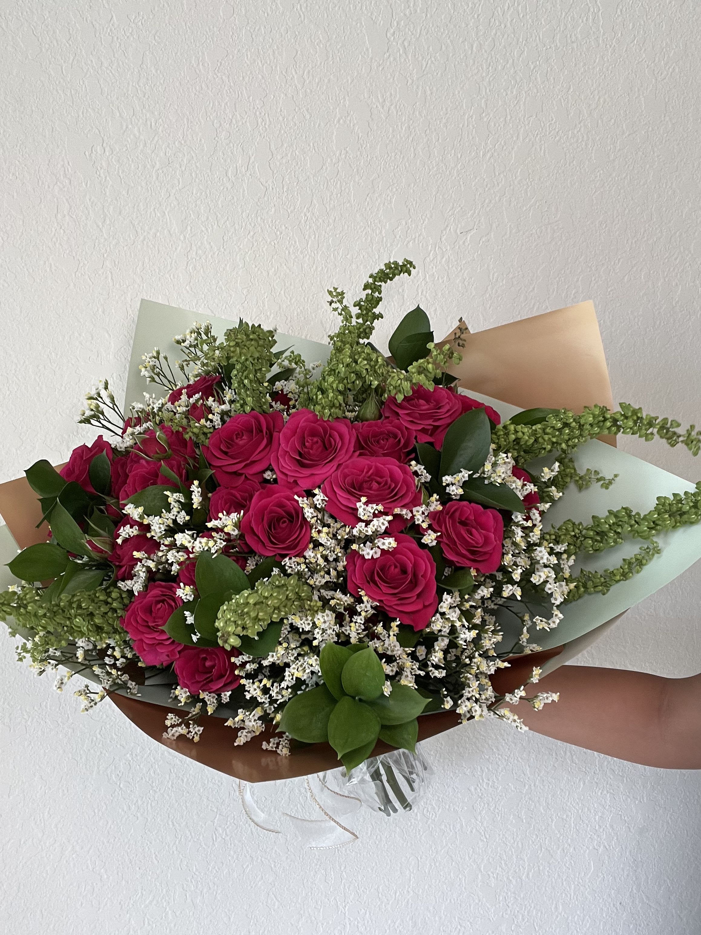 Bouquet of hot pink roses with white filler flowers and greenery