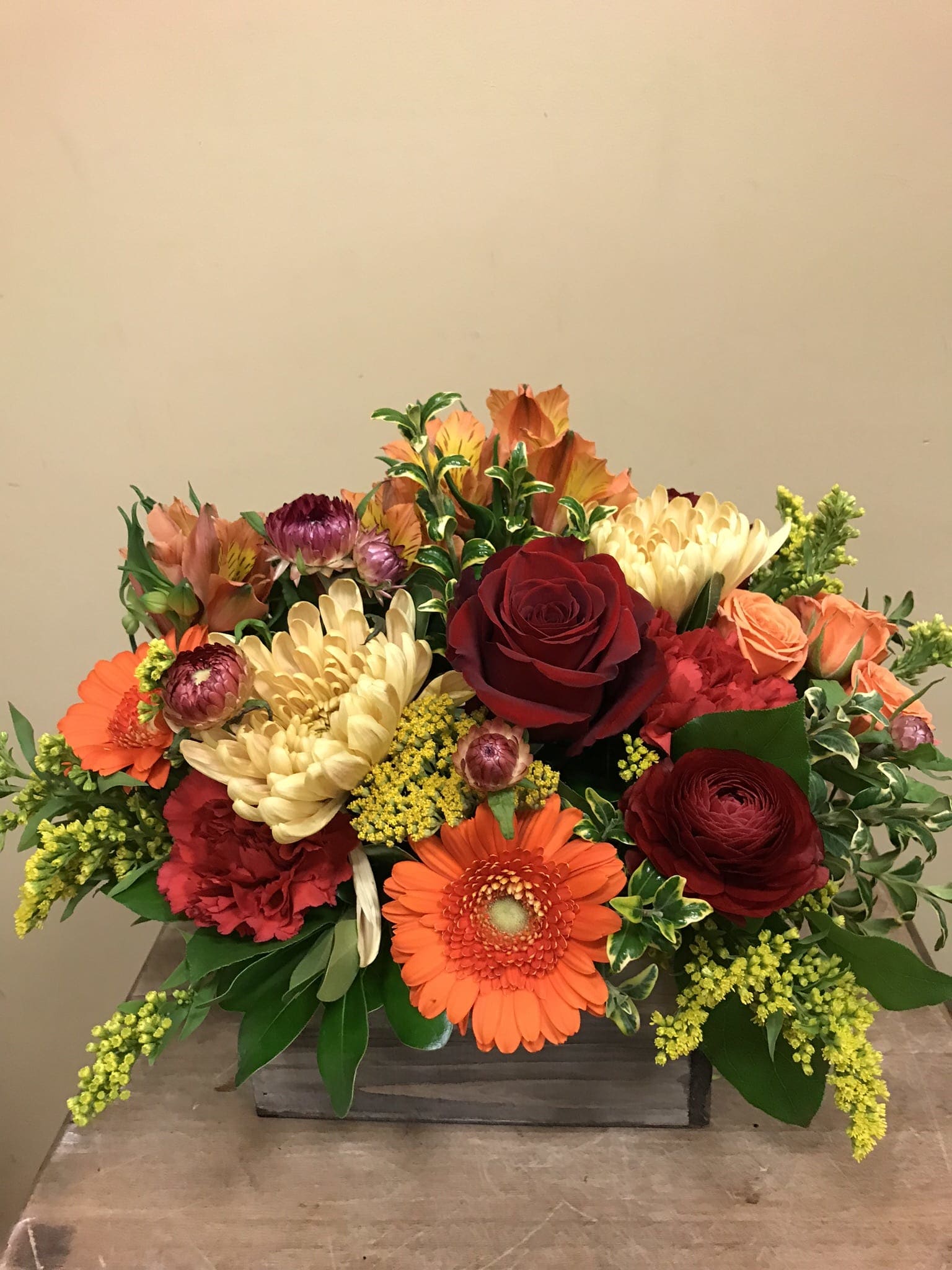 Mixed bouquet with red roses, orange gerberas, and cream chrysanthemums in a wooden box
