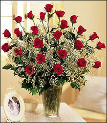 Red roses arranged in a clear glass vase with baby's breath