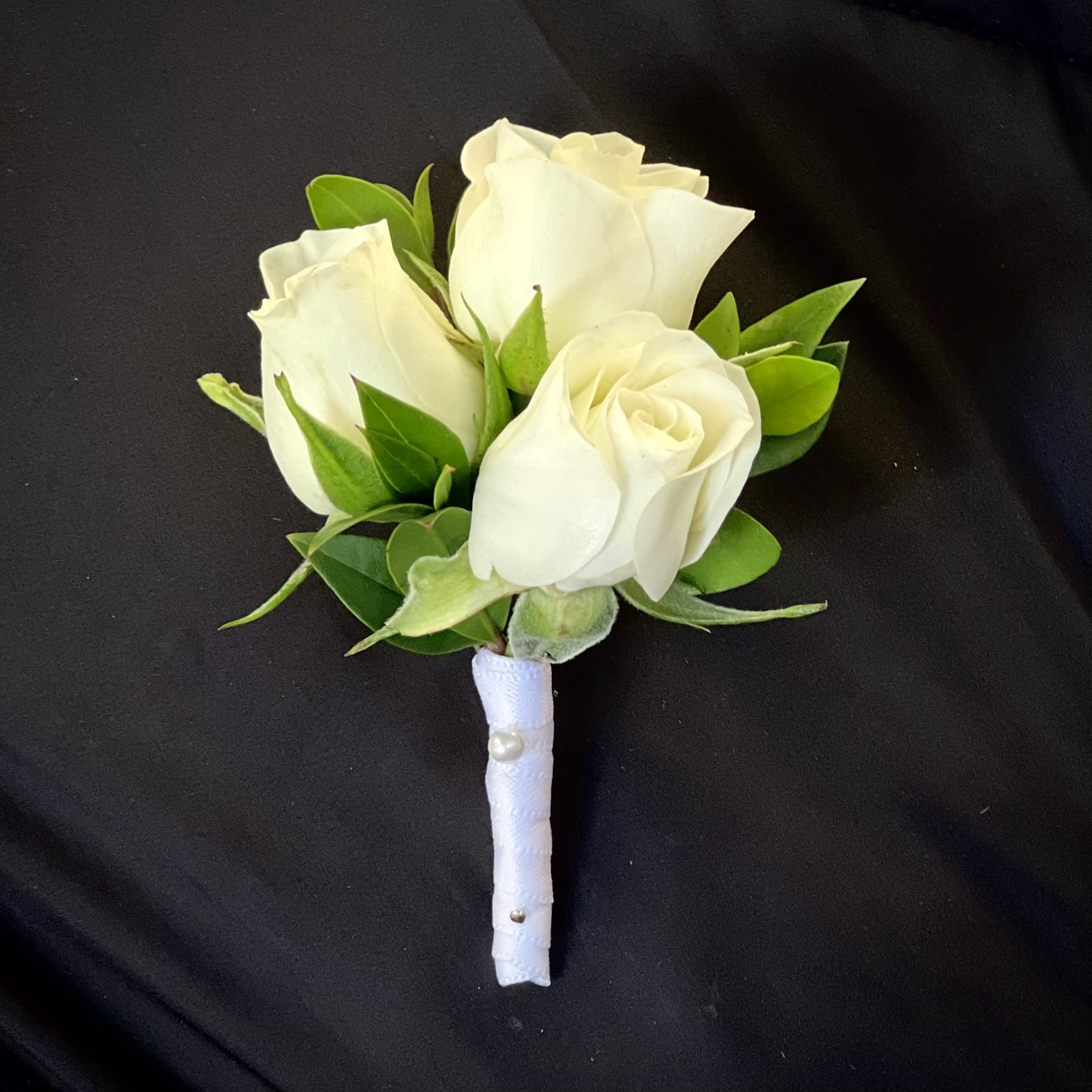 White rose boutonniere with green leaves and a wrapped stem