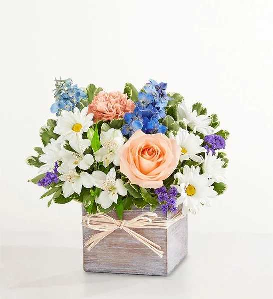Coastal Breeze™ - About Coastal Breeze™ EXCLUSIVE Inspired by the soothing shades of a seaside retreat, our popular bouquet will bring its tranquil beauty to someone special. Roses, delphiniums, Peruvian lilies, and other favorites are artistically designed in our gray-washed wooden cube finished with a touch of raffia to deliver your sentiments in cool, summery style.