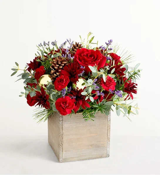 Russet Charm™ - About Russet Charm™ NEW Our arrangement is as bracing and beautiful as a walk through the woods on a crisp winter day. Roses and other blooms in rich reds and burgundies are surrounded by lush Christmas foliage, pinecones, and petite golden balls in a gray-washed wooden cube. This gift will feel right at home on a table, a windowsill, a mantel… just about anywhere!