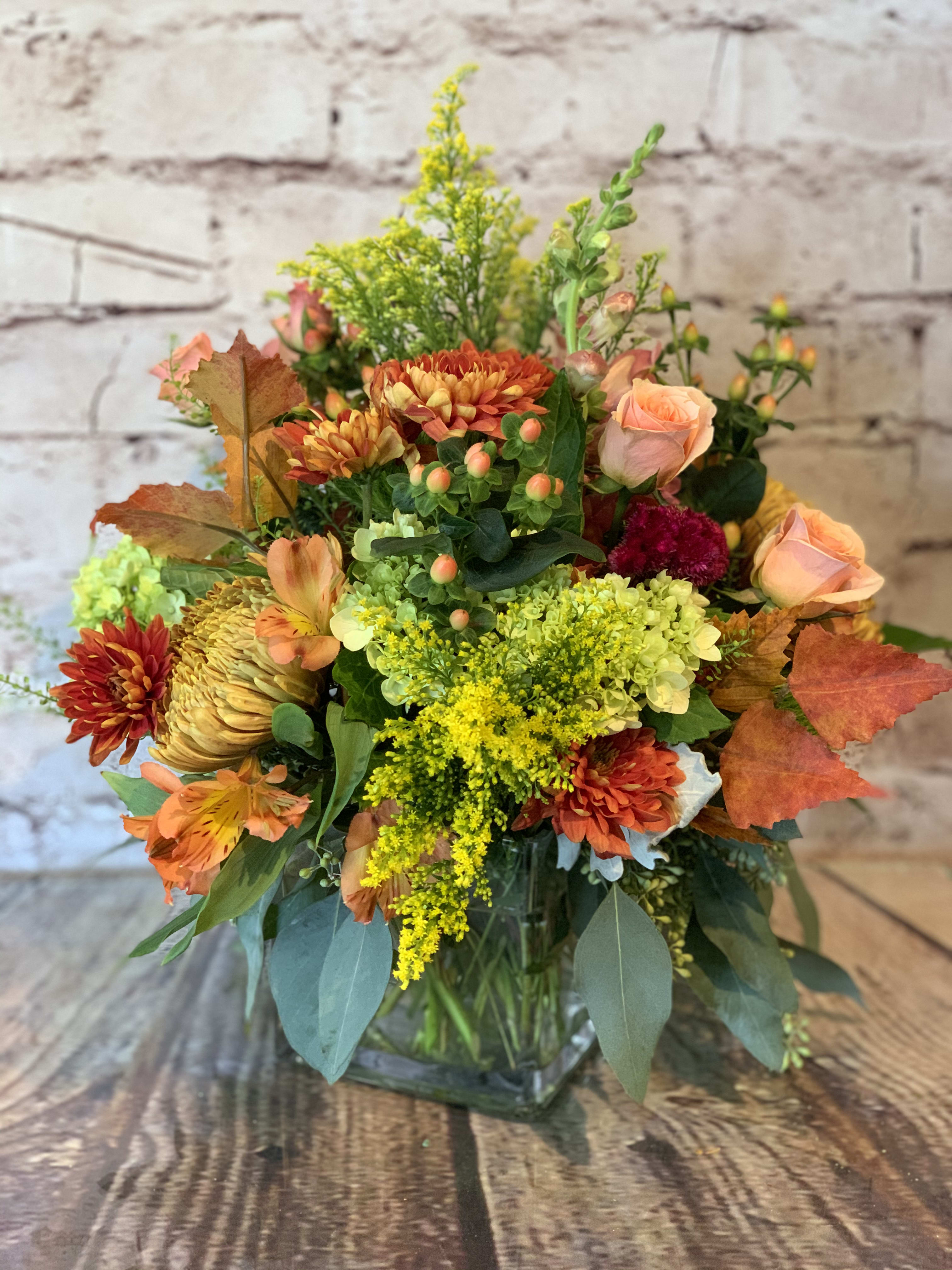 Autumn bouquet with orange and yellow flowers in a clear glass vase