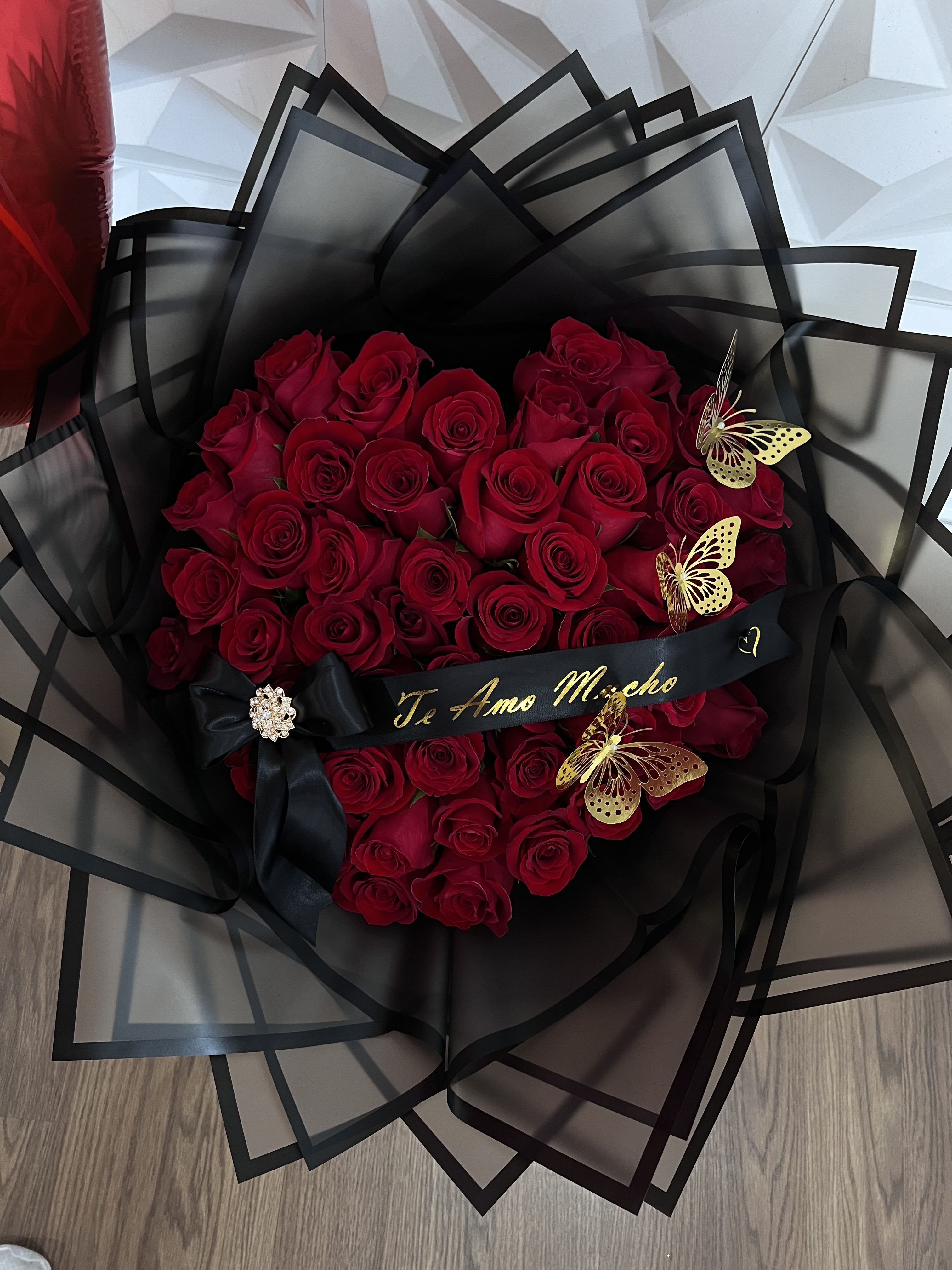 Bouquet of red roses wrapped in black paper with butterfly accents