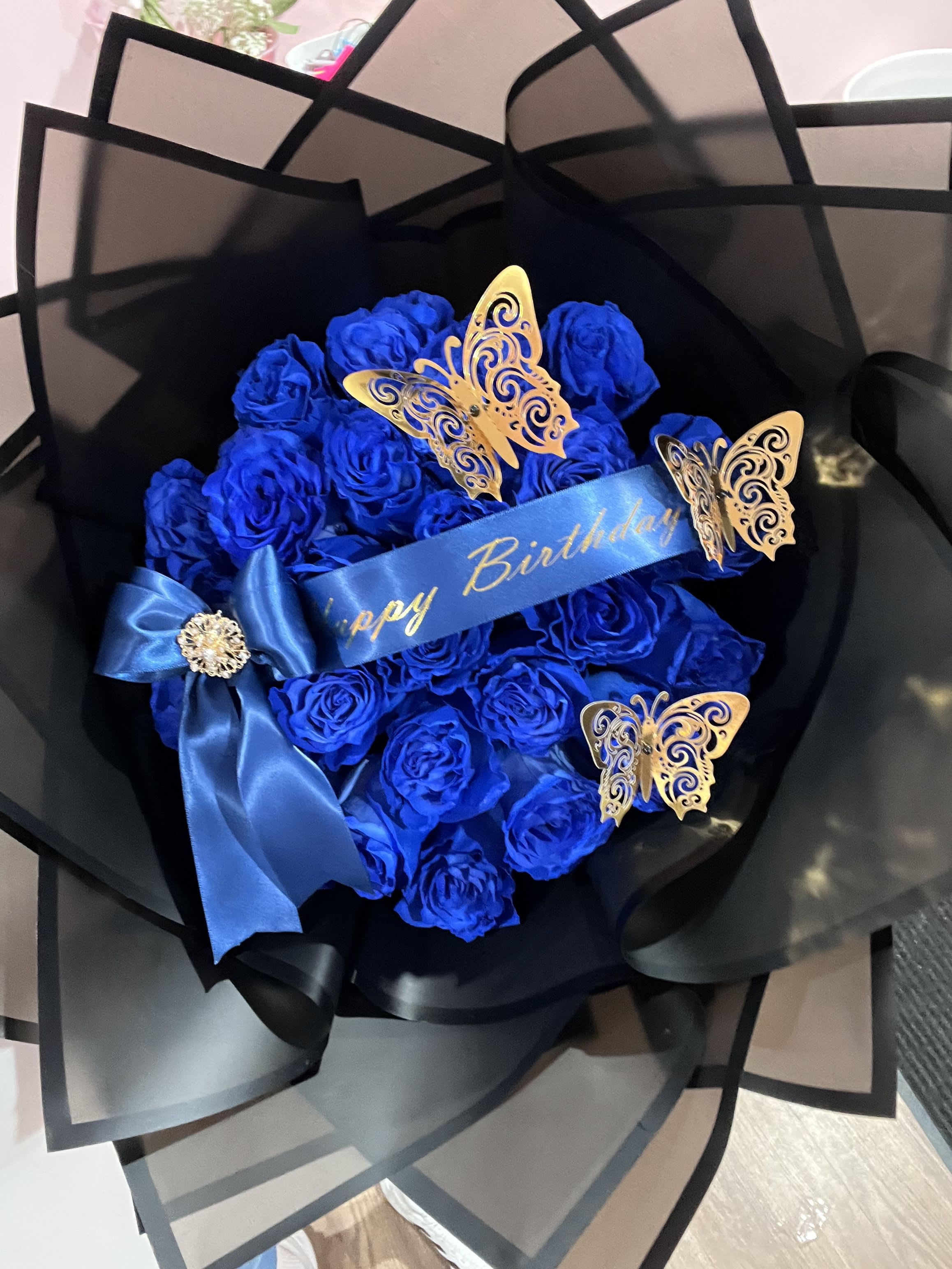 Blue rose bouquet with a birthday ribbon and butterfly decorations