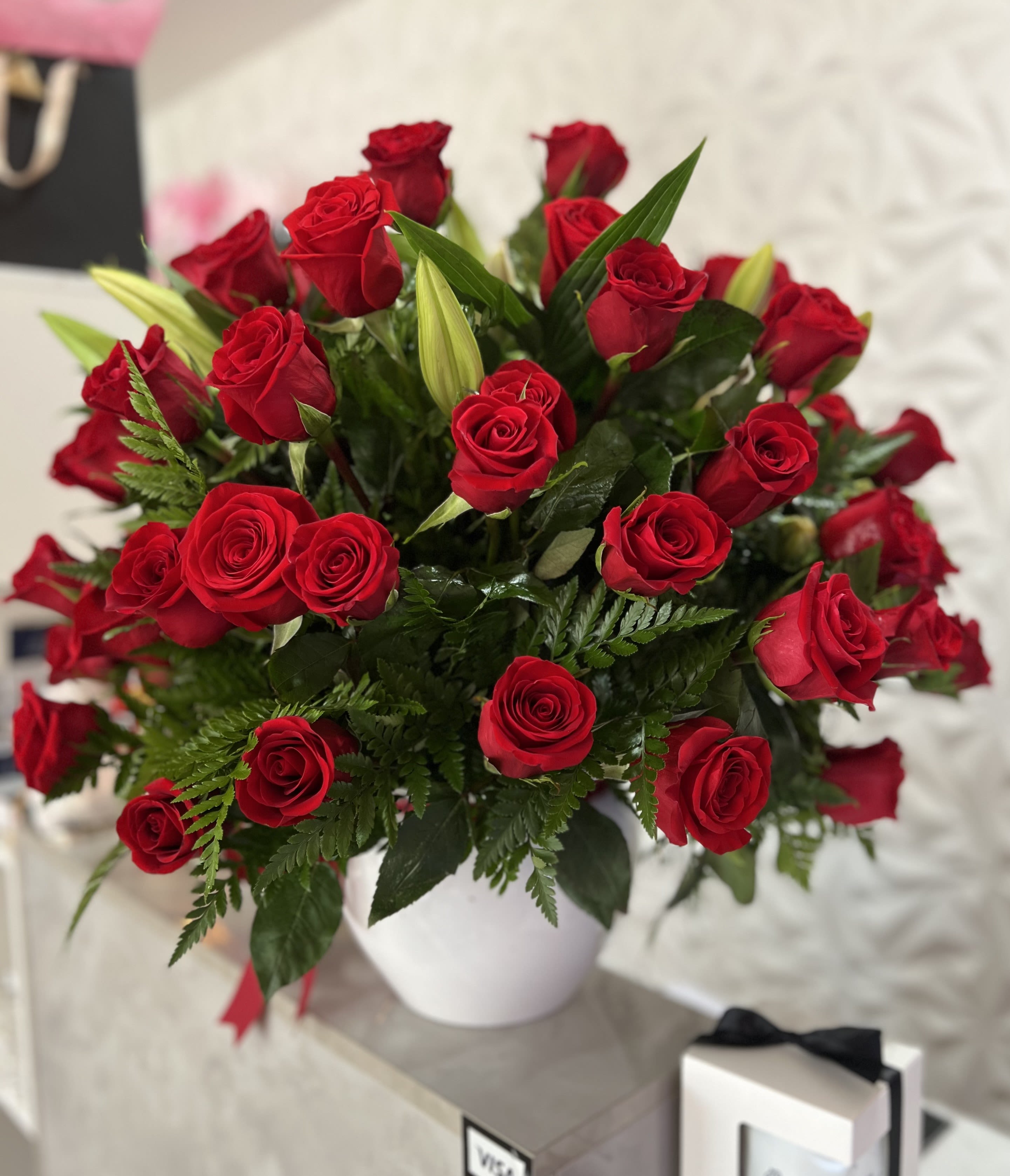 Bouquet of red roses in a white vase with green foliage
