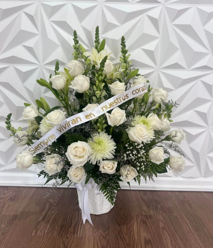 White rose and lily arrangement in a white basket with a ribbon