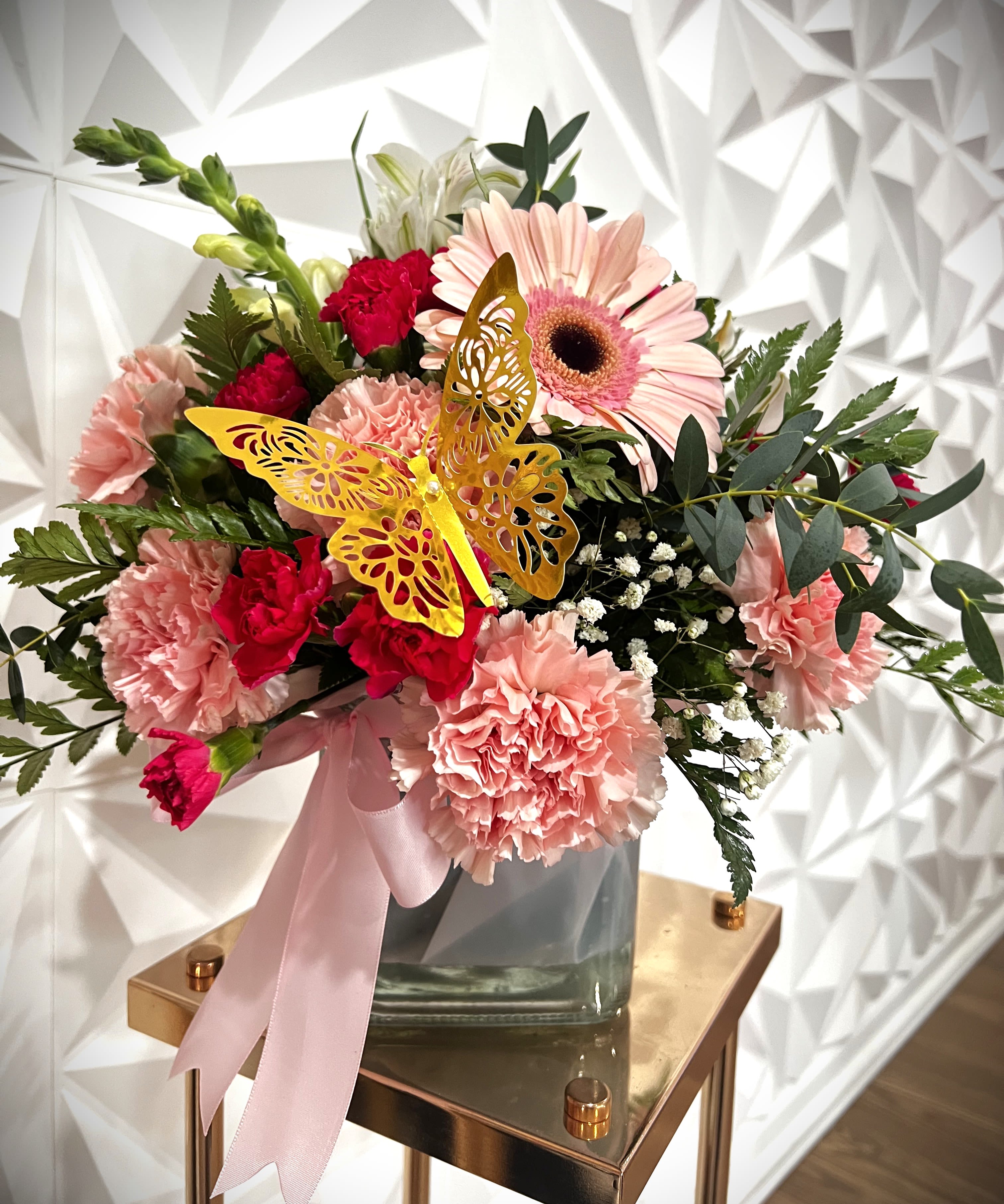 Pink and red mixed bouquet in a glass vase with a butterfly decoration